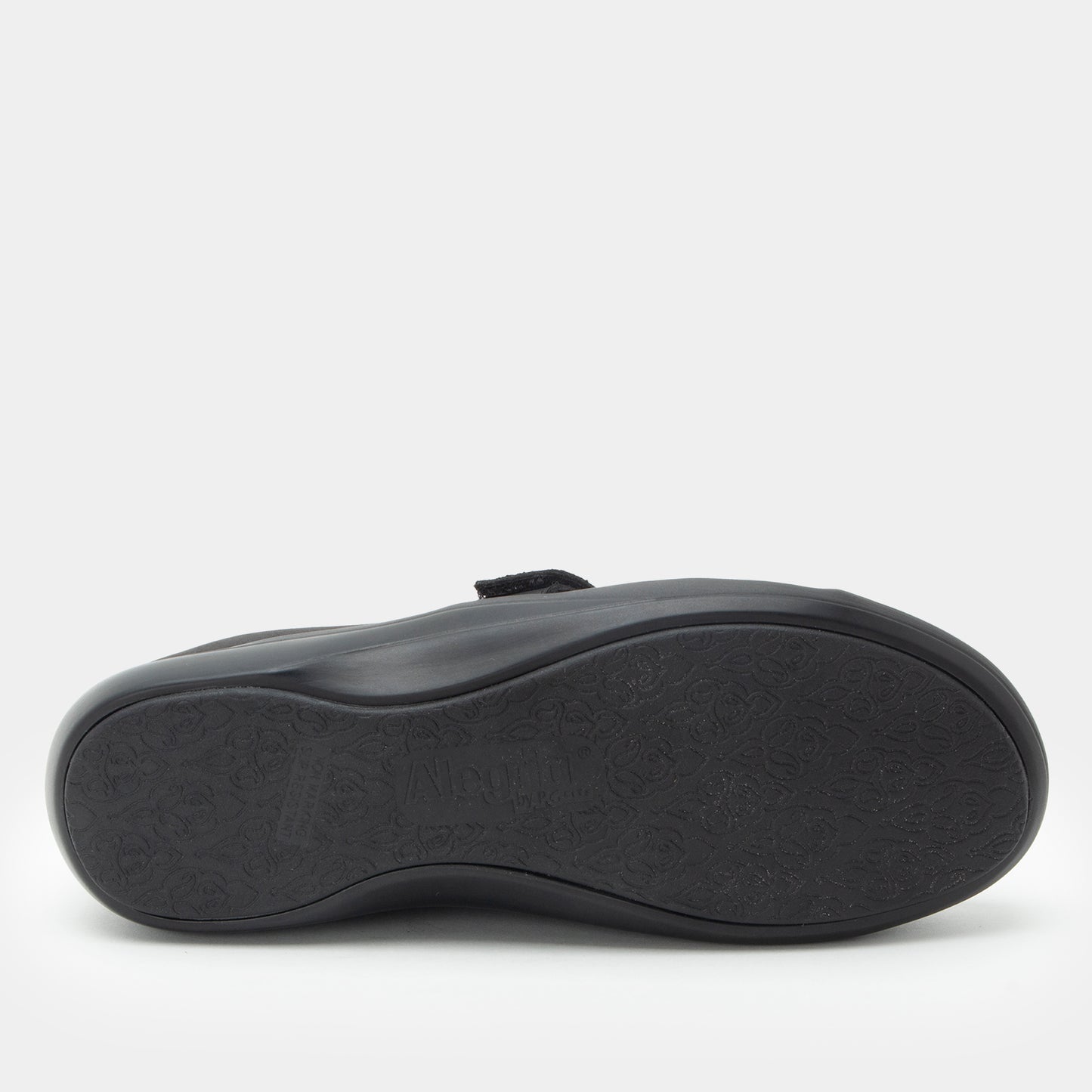 A close-up, top-down view of a black shoe sole, showing the textured rubber tread and a small black strap detail, set against a clean white background.