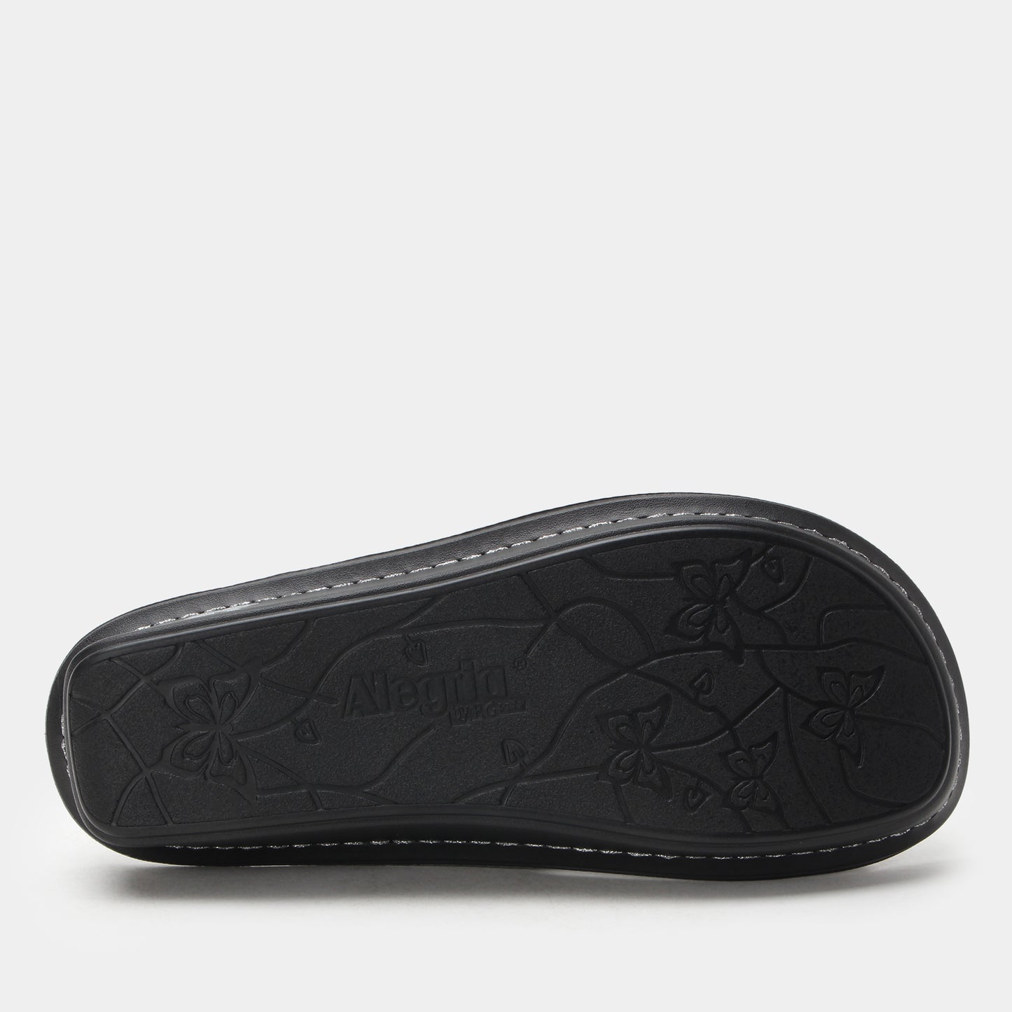 Black sandal sole with floral patterns and brand name on a light gray background
