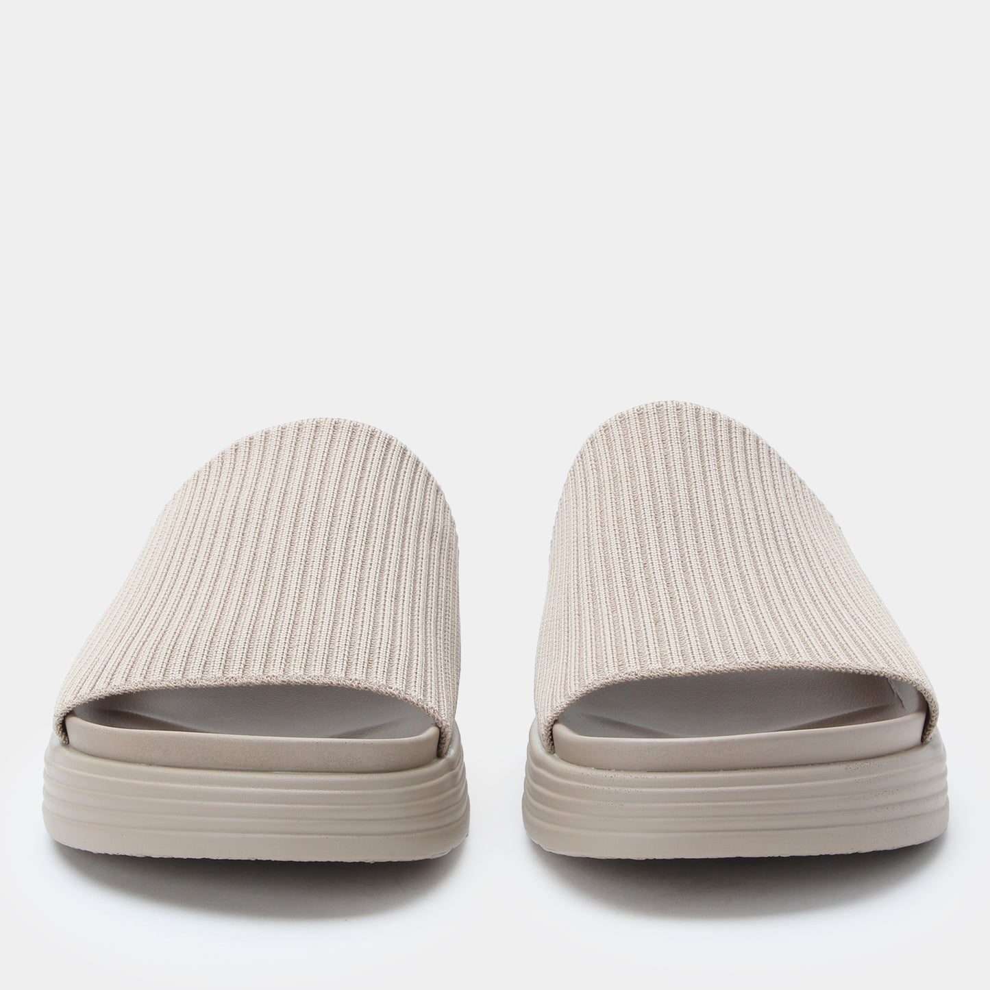 Pair of beige slides with ribbed texture on a white background