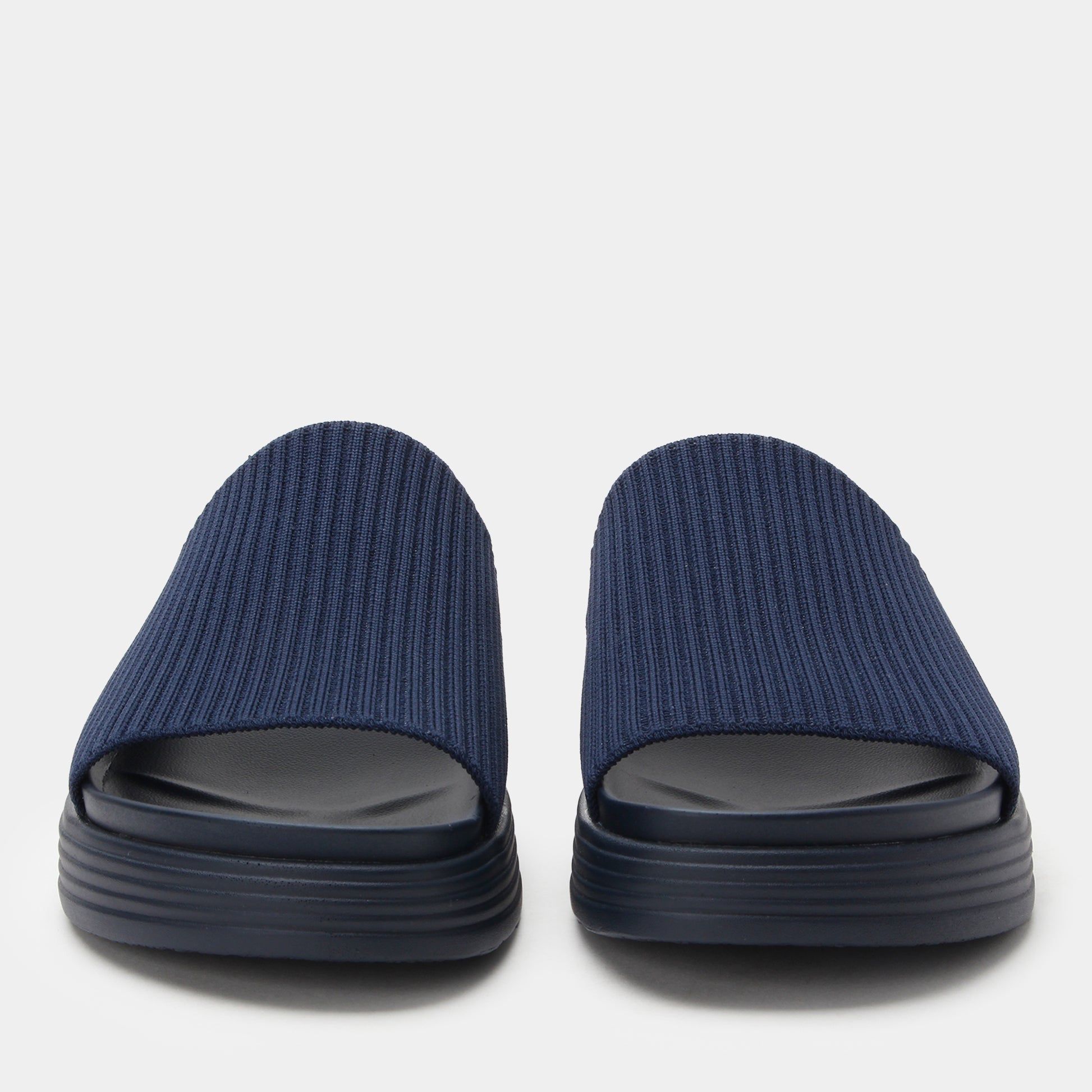 Pair of navy blue slides with black soles on a light gray background