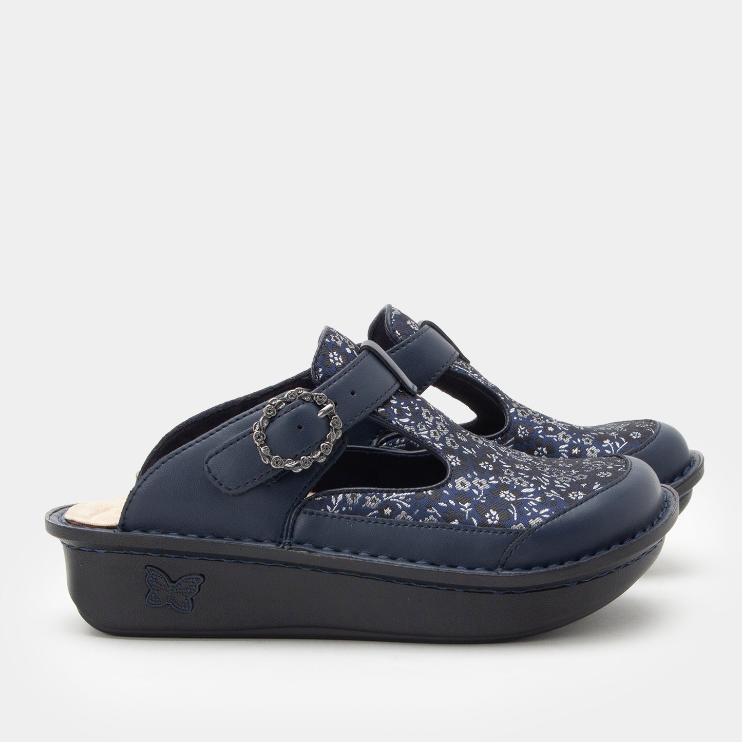 Navy blue clogs with floral pattern on a light gray background