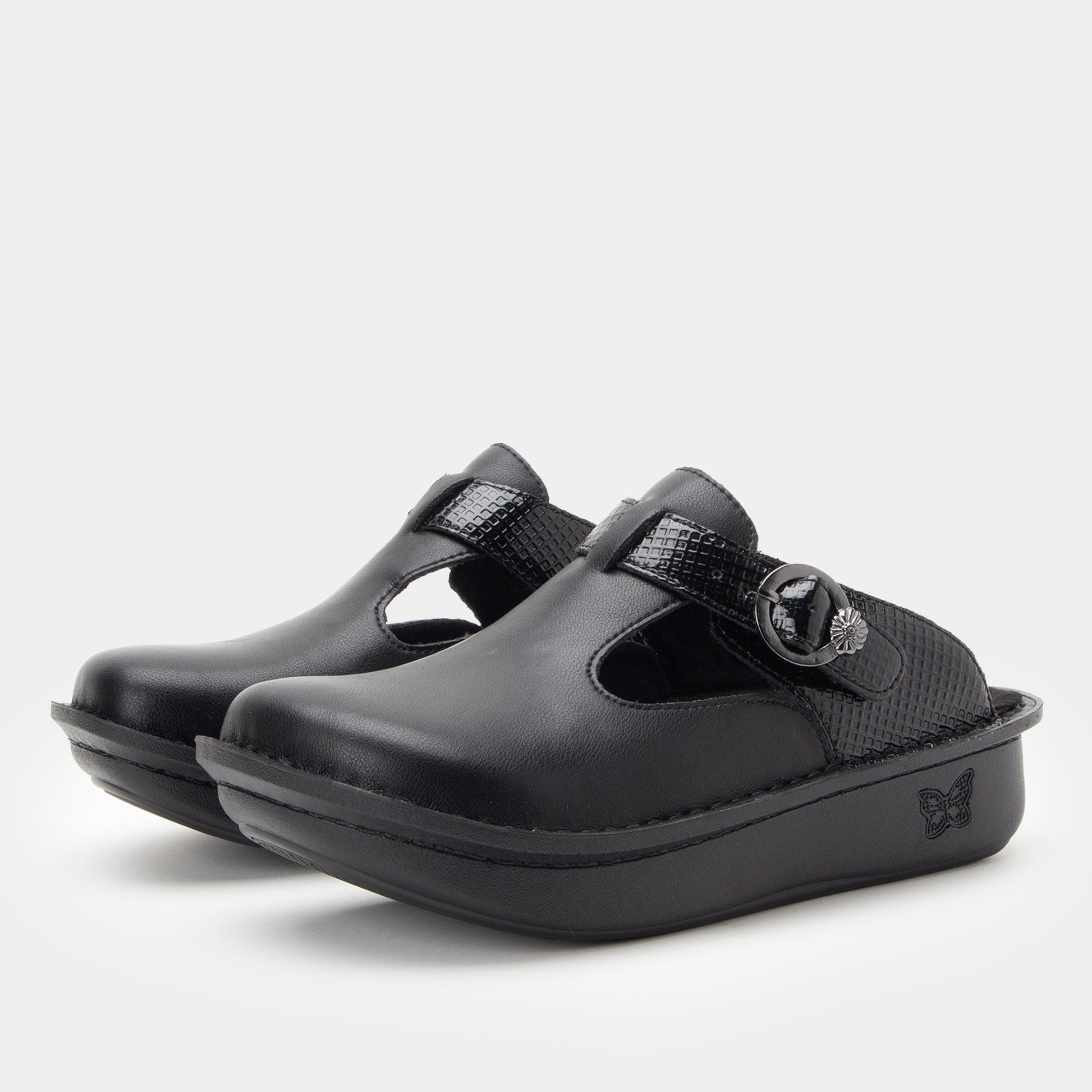 Pair of black clogs with a buckle on a light gray background
