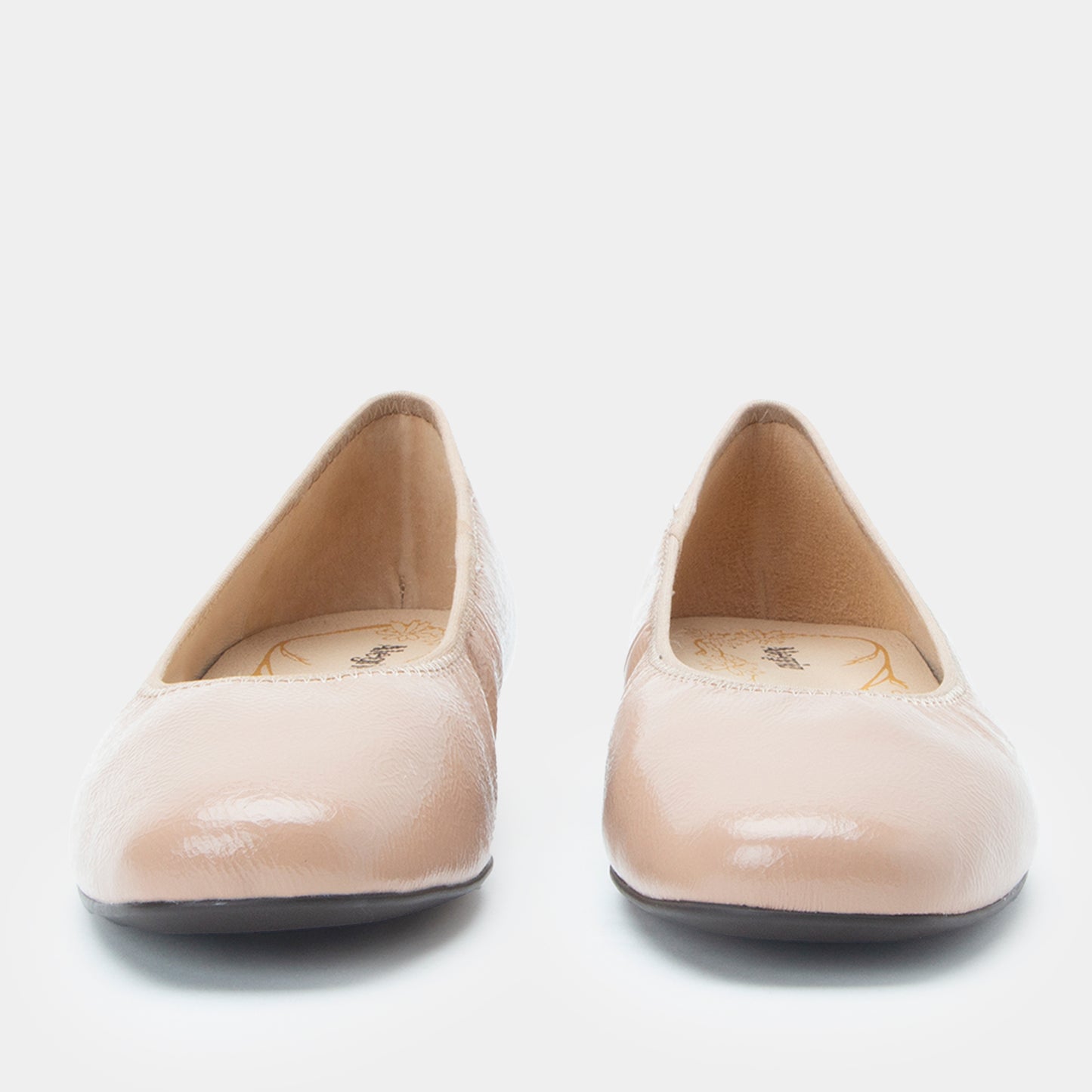 Pair of beige patent leather shoes on a white background