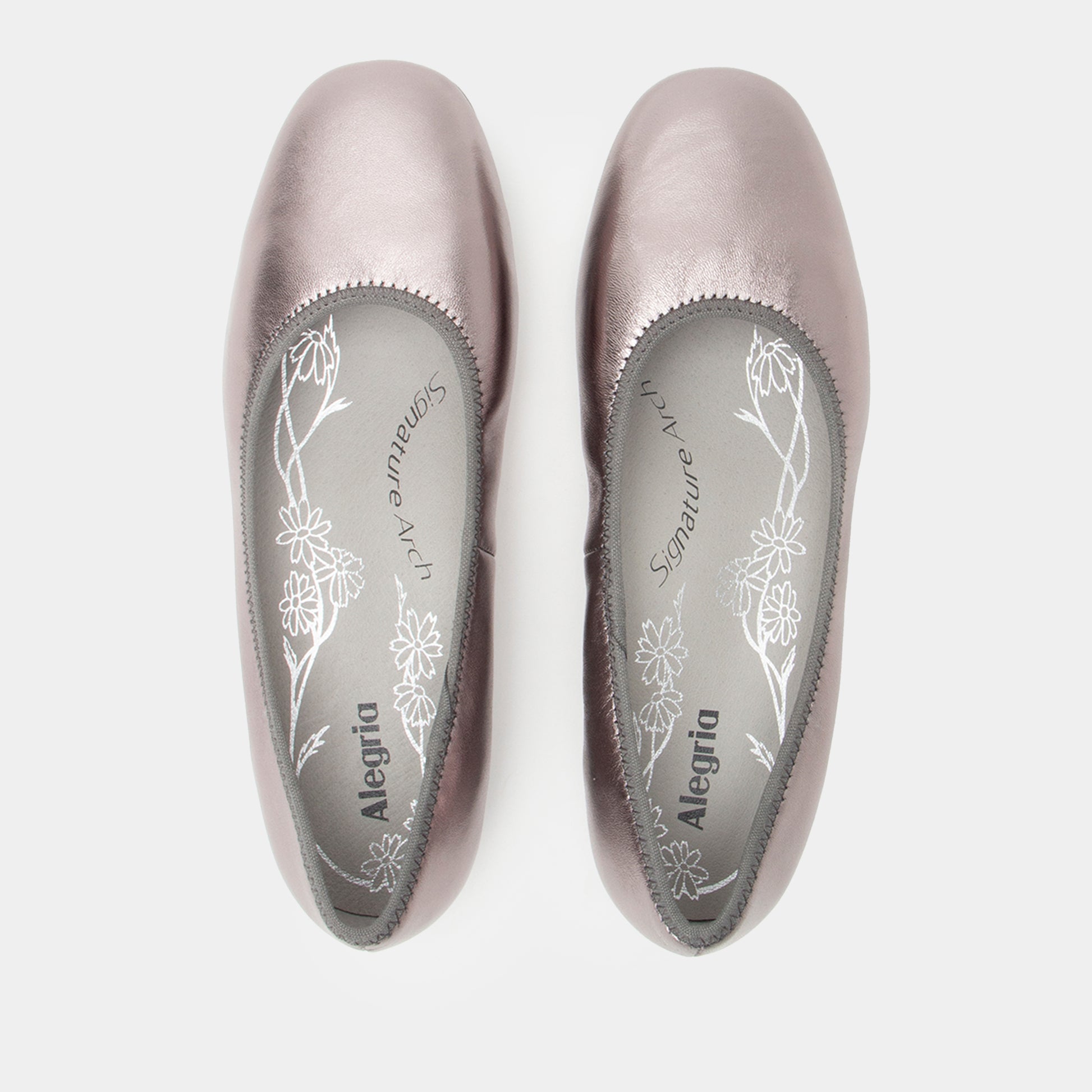 Pair of silver ballet flats with floral design on a white background
