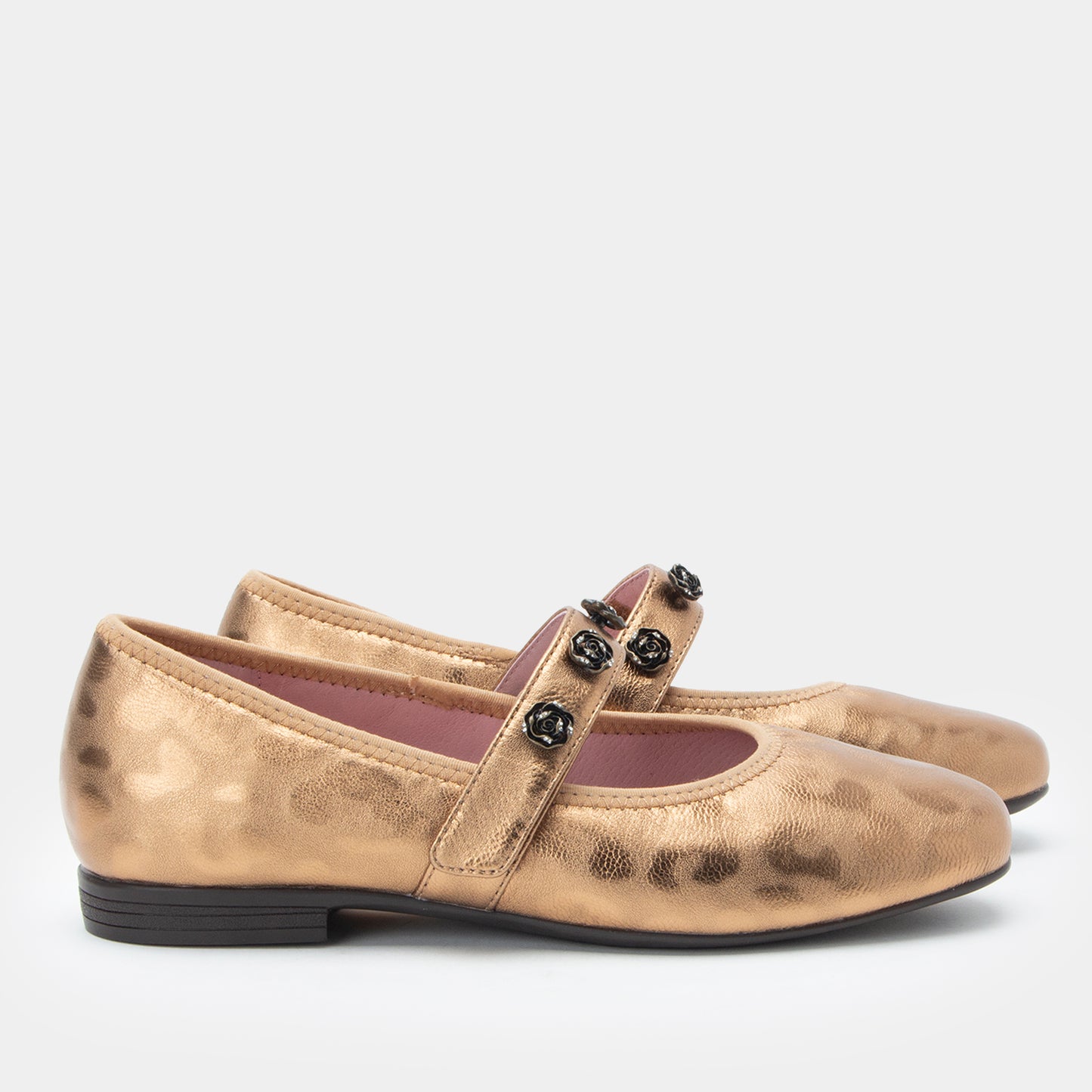 Gold metallic flat shoes with a strap and black buckles on a white background