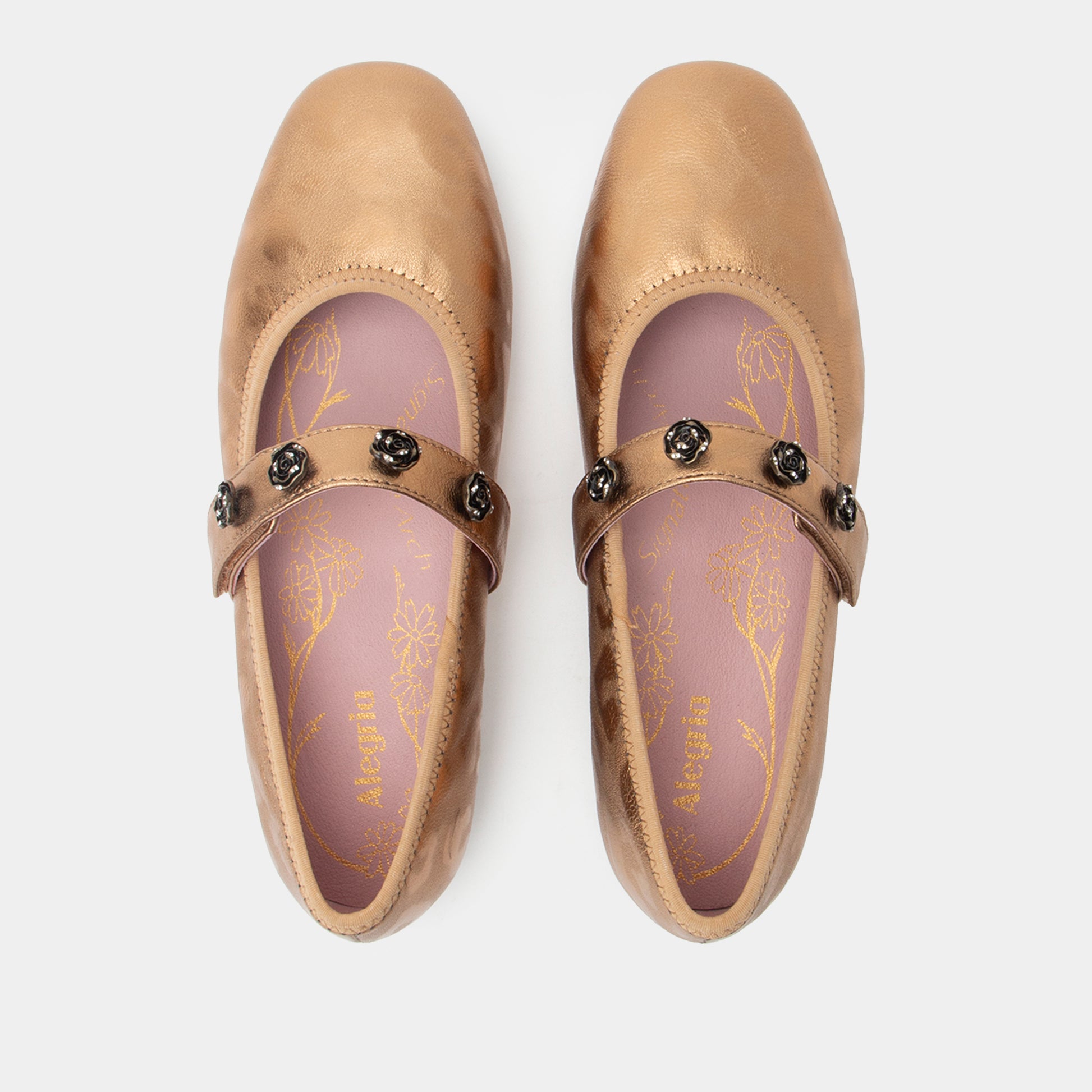 Pair of gold flats with decorative straps on a white background