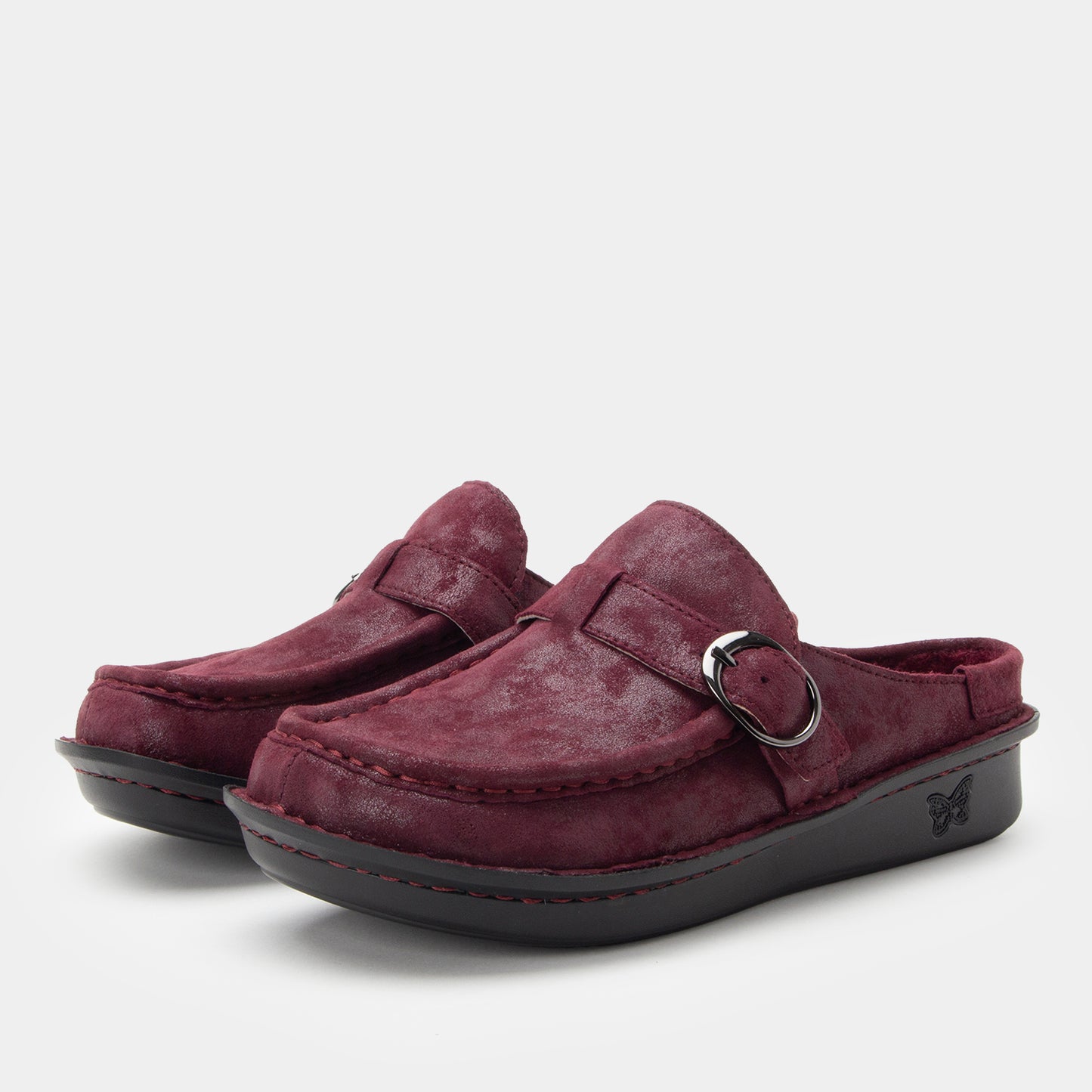 Pair of maroon suede shoes with a buckle on a light gray background