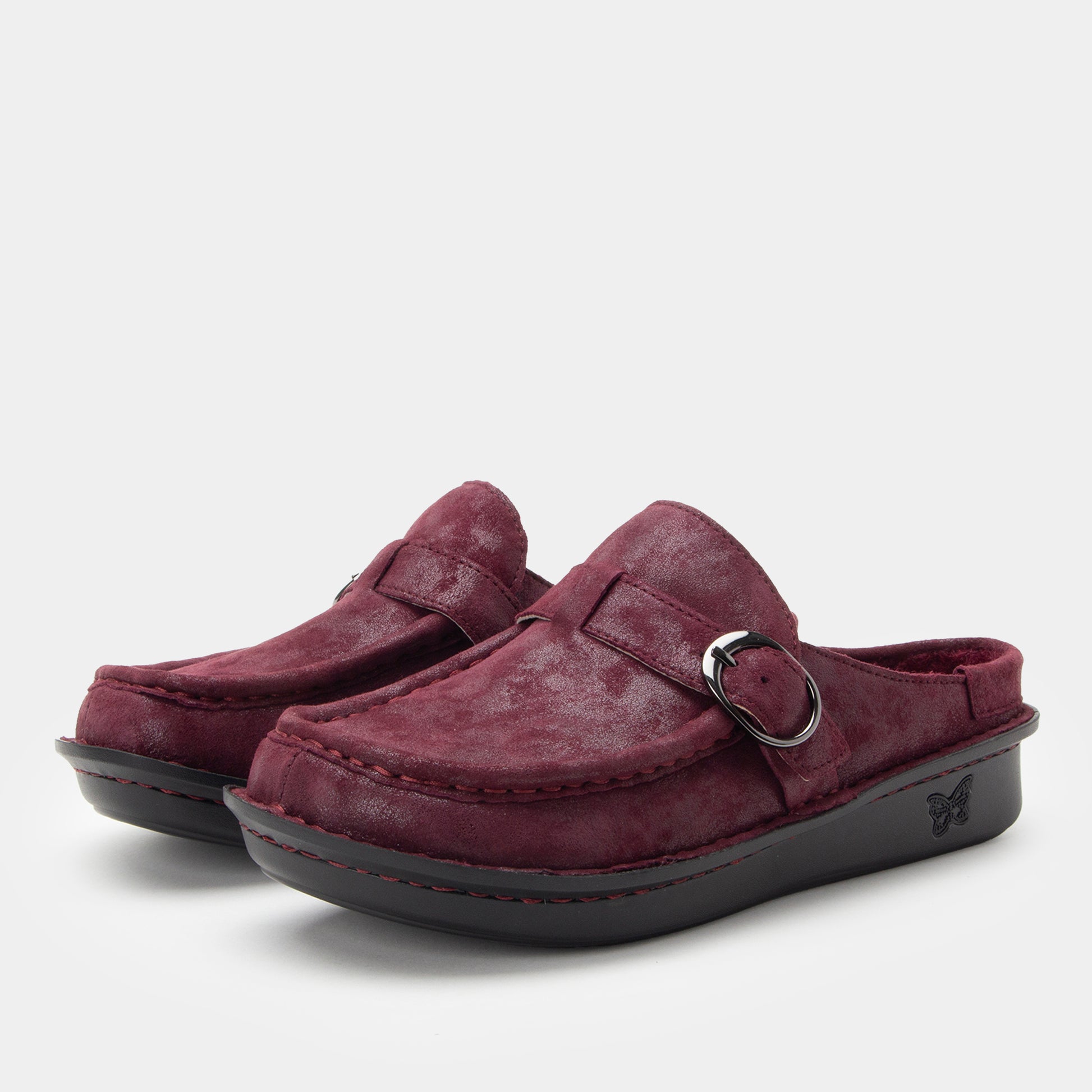 Pair of maroon suede shoes with a buckle on a light gray background