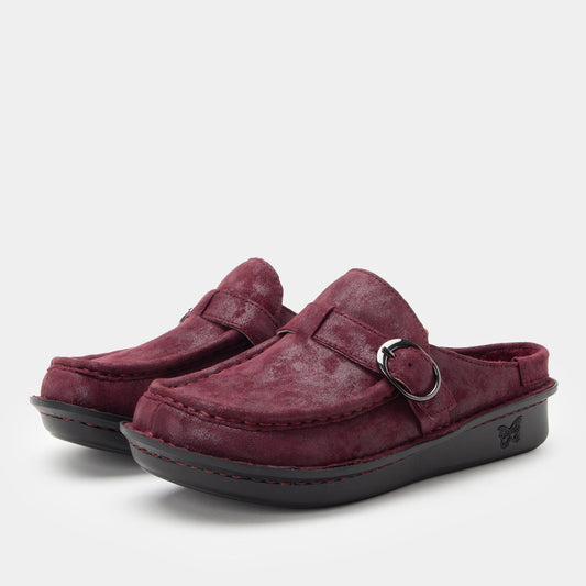 Pair of maroon suede shoes with a buckle on a light gray background