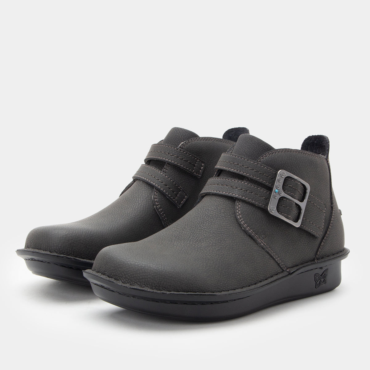 Pair of grey boots with buckles on a light gray background