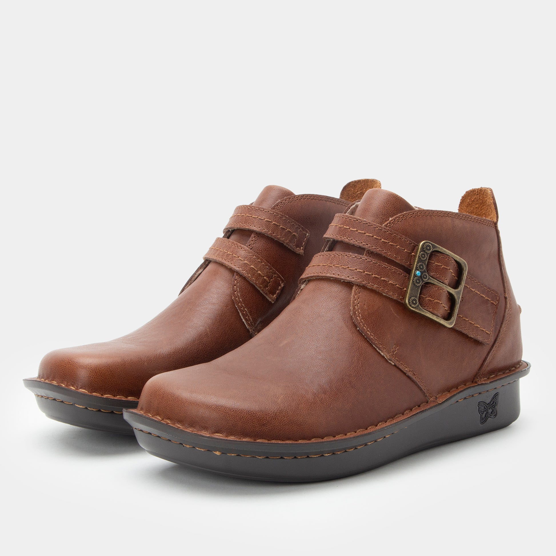 Pair of brown leather boots with buckles on a light gray background