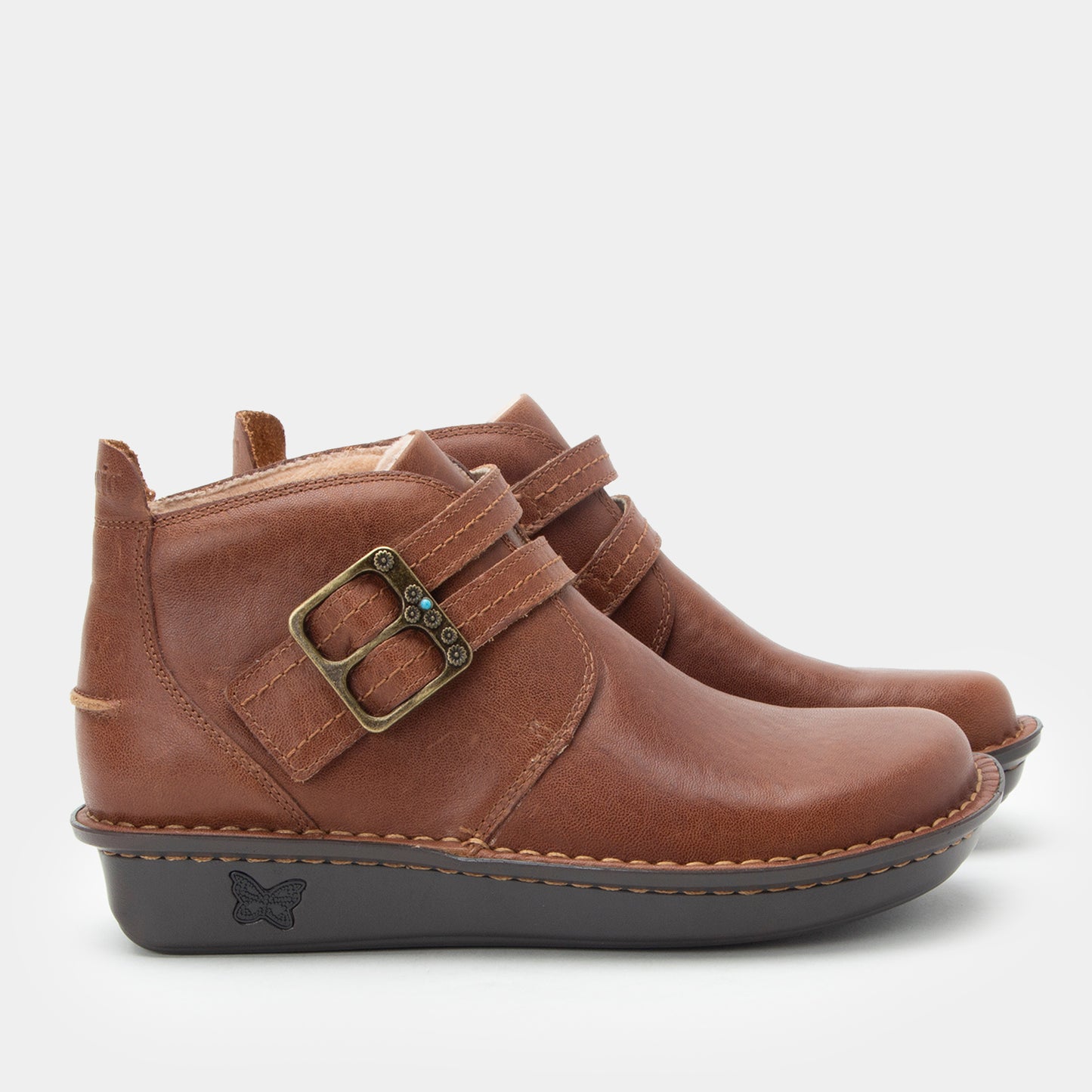 Brown leather ankle boots with a buckle on a light gray background