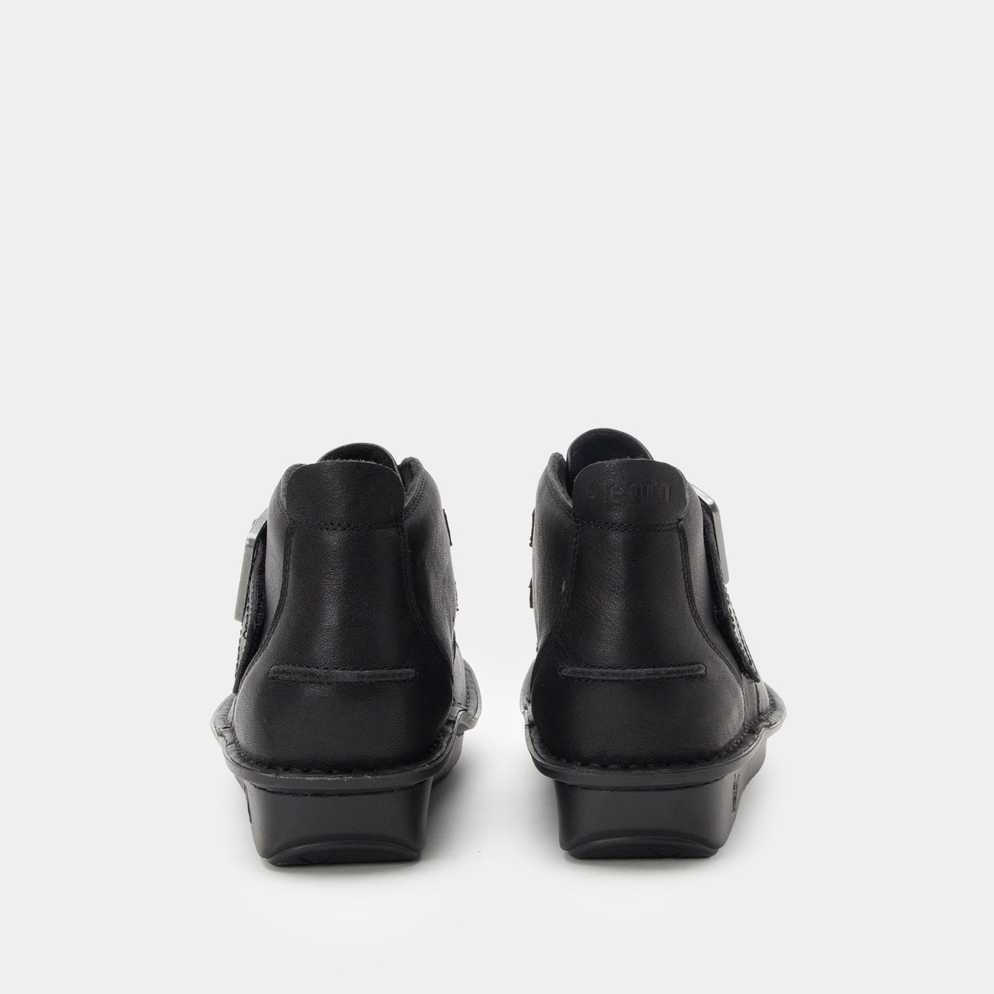 A pair of black leather ankle boots shown from the back, featuring side zippers and low block heels, set against a plain light gray background.