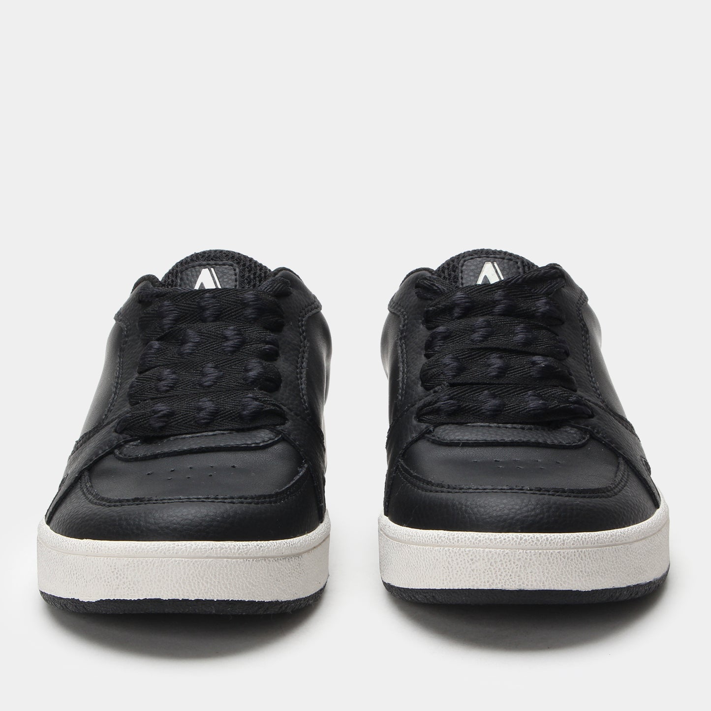 Black sneakers with white soles on a light gray background