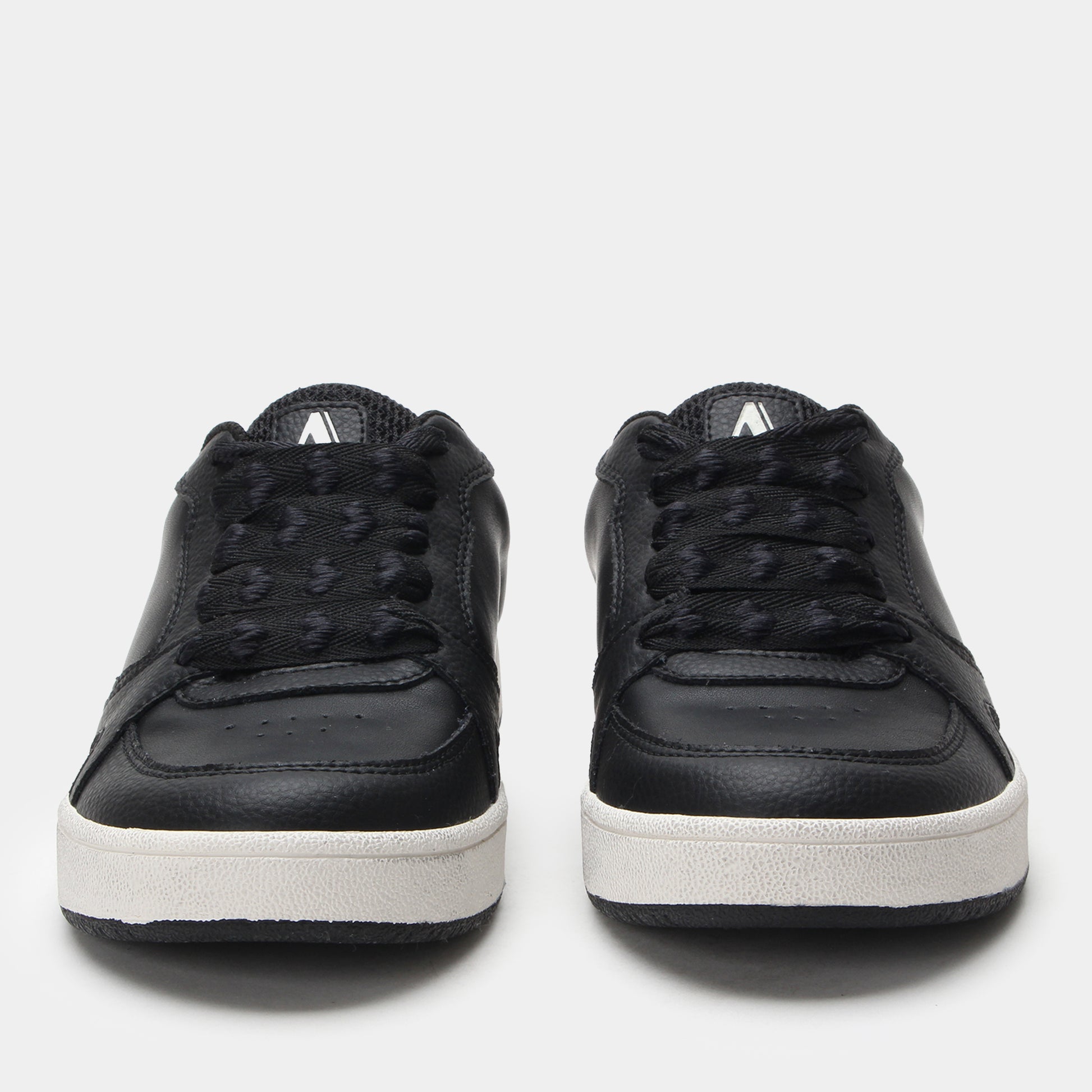 Black sneakers with white soles on a light gray background