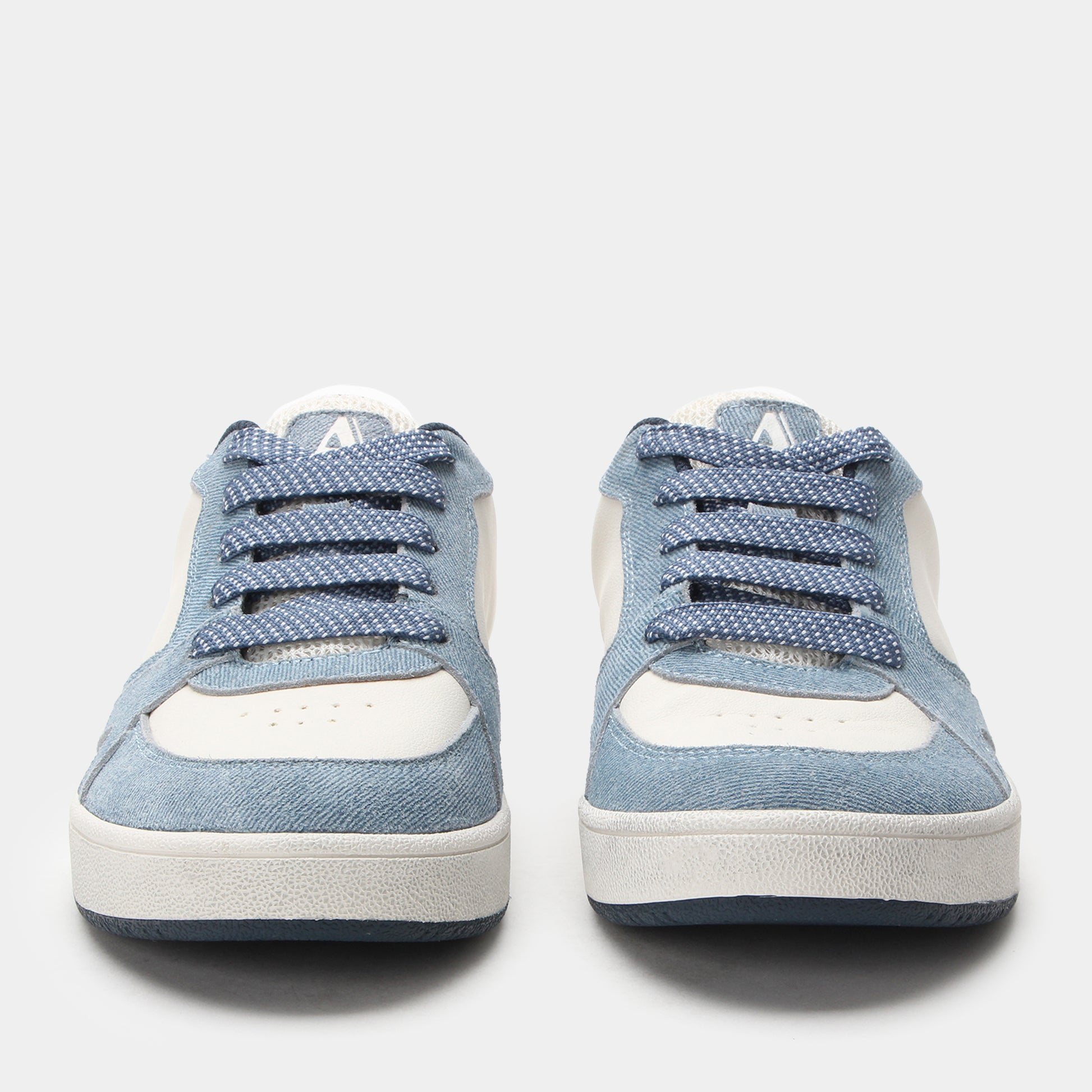 Pair of blue sneakers with white soles on a light gray background