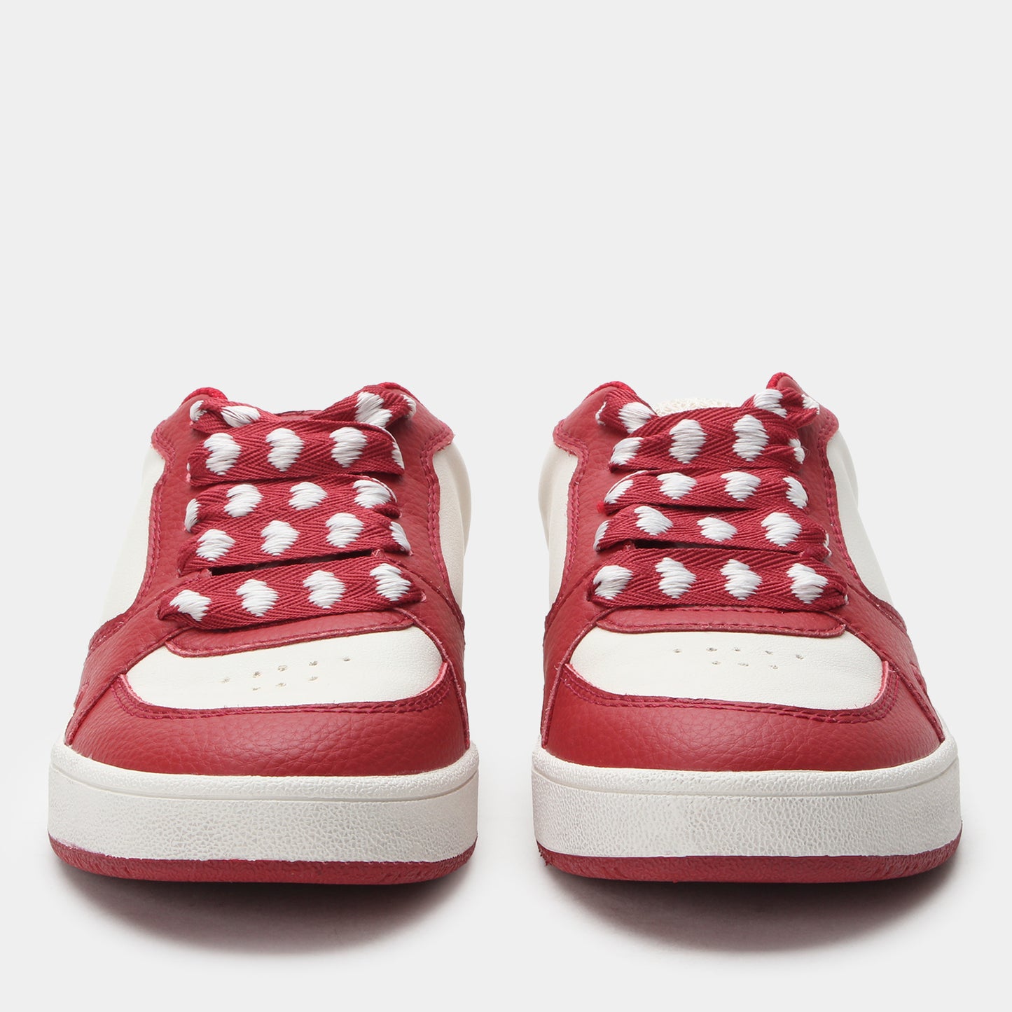 Red sneakers with white hearts on a light gray background