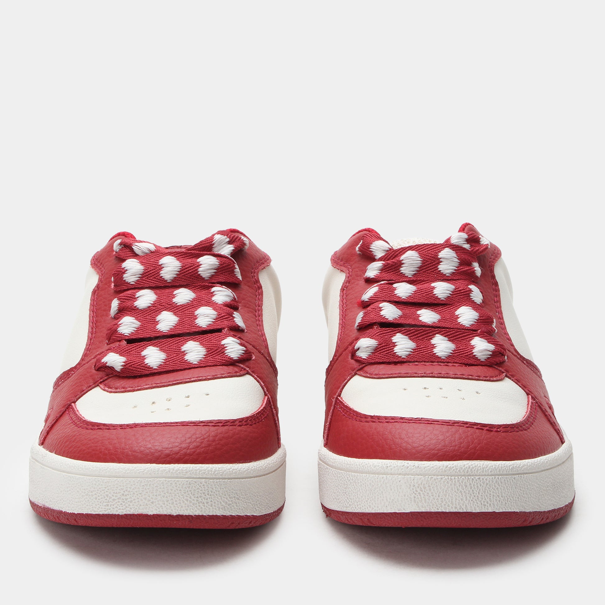 Red sneakers with white hearts on a light gray background
