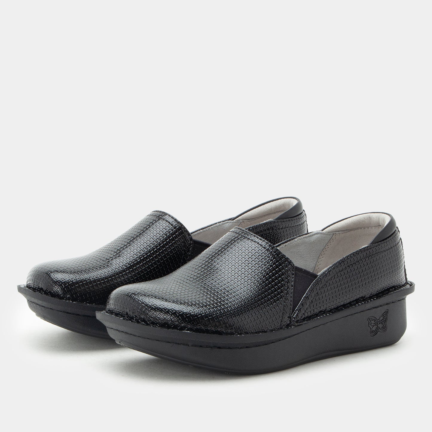 A pair of women's black slip-on platform shoes with a textured, reptile-like patterned upper, shown on a light gray background.