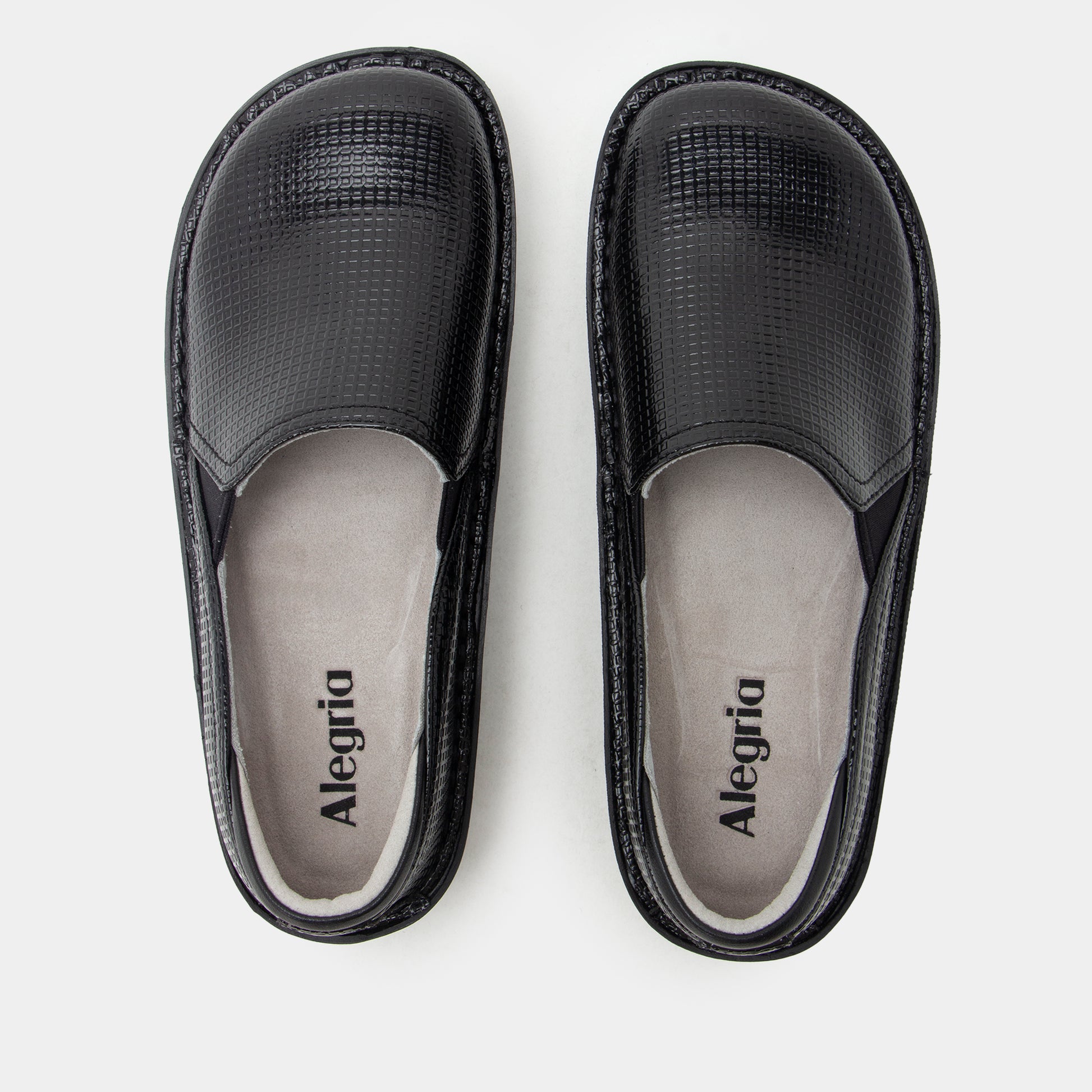 A pair of black slip-on shoes with textured faux-croc uppers and light gray insoles, shown from a top-down view on a light gray background. The brand name 'Alegria' is printed on the insoles.