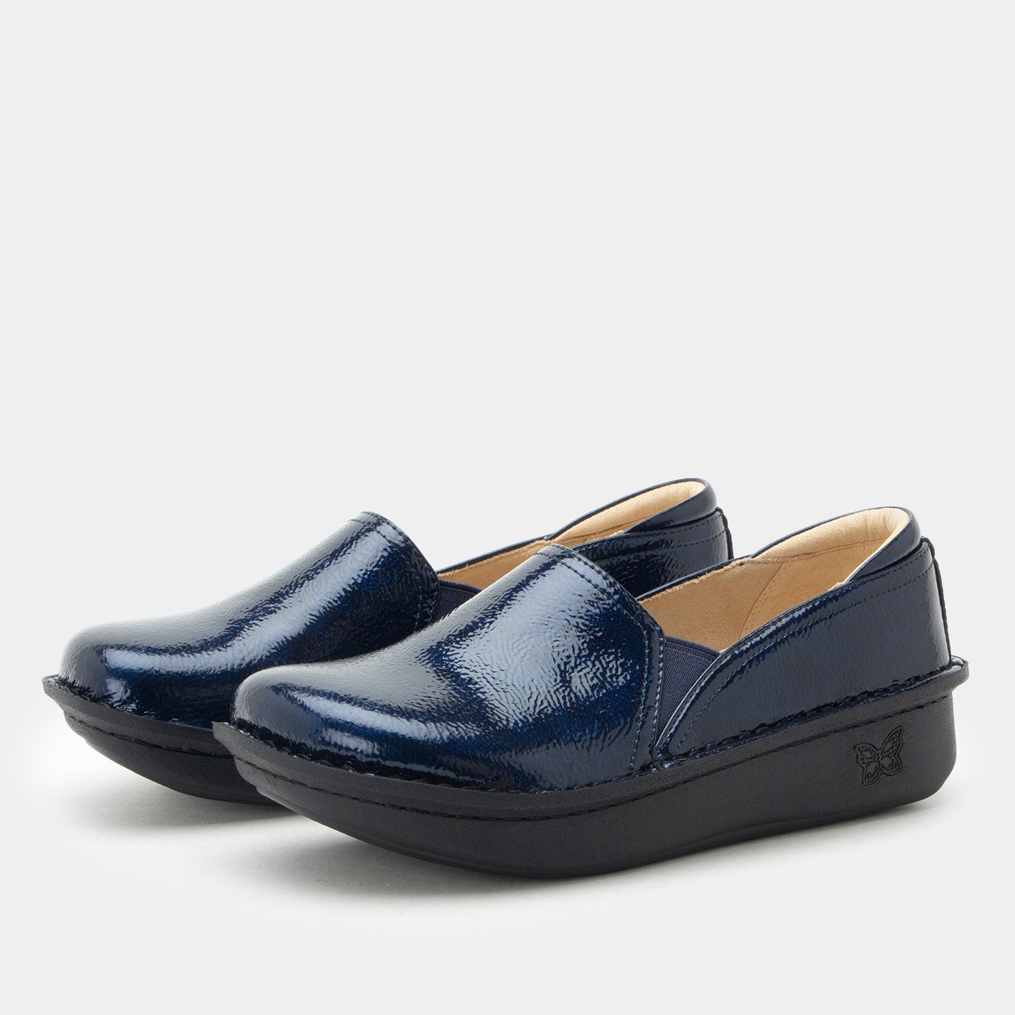 A pair of navy blue patent leather slip-on shoes with black platform soles, displayed on a clean light gray background.