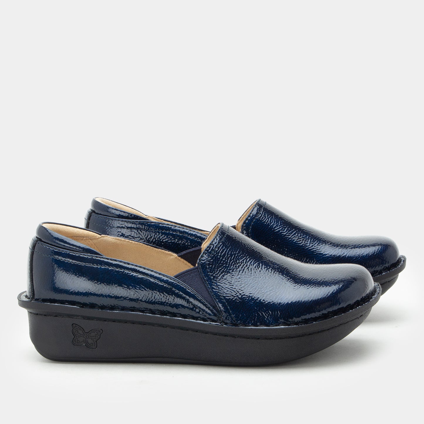 A pair of navy blue patent leather slip-on shoes with black platform soles, shown against a light gray background.