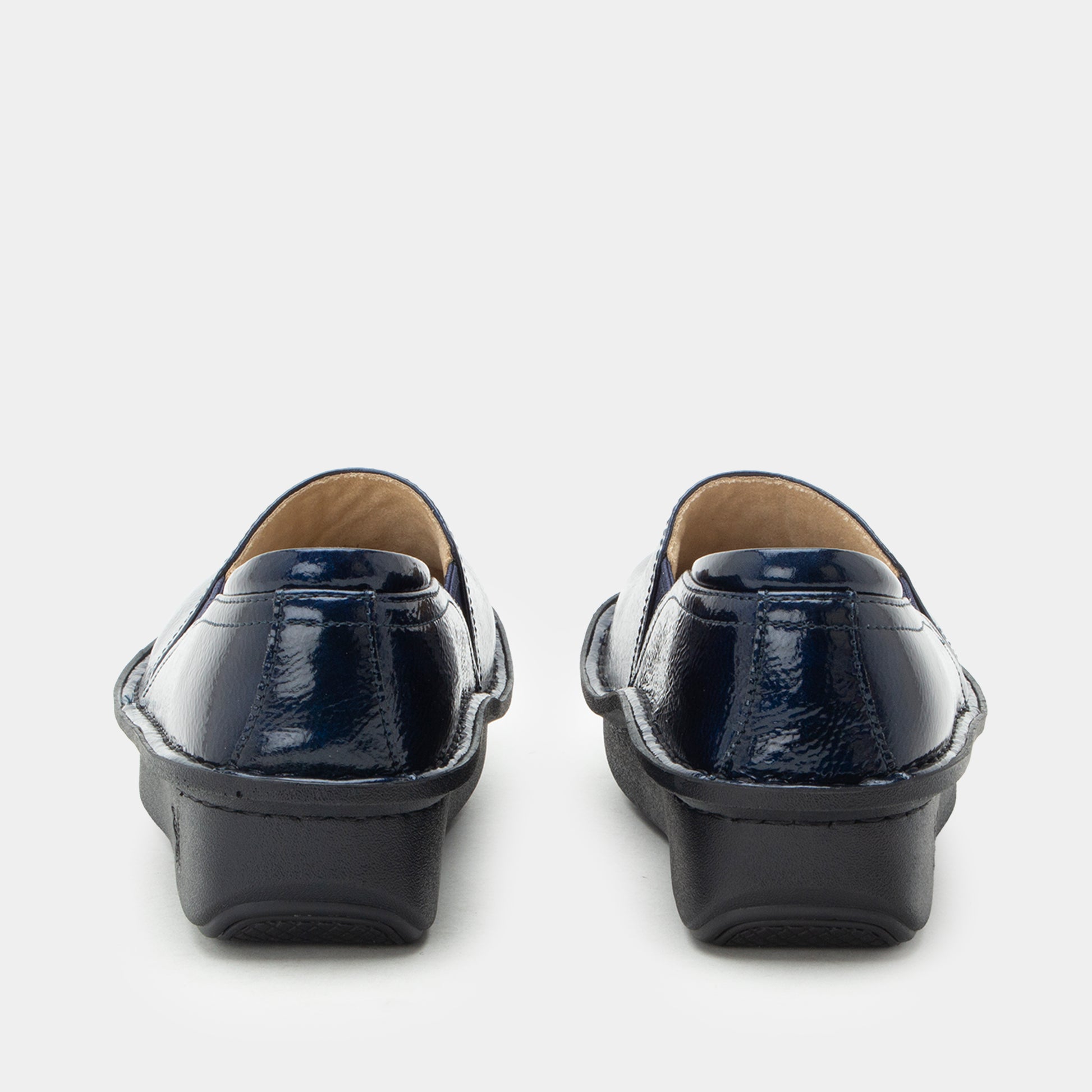 A pair of women's slip-on loafers shown from the back, featuring a glossy navy blue patent leather upper and a chunky black platform sole, set against a plain light gray background.