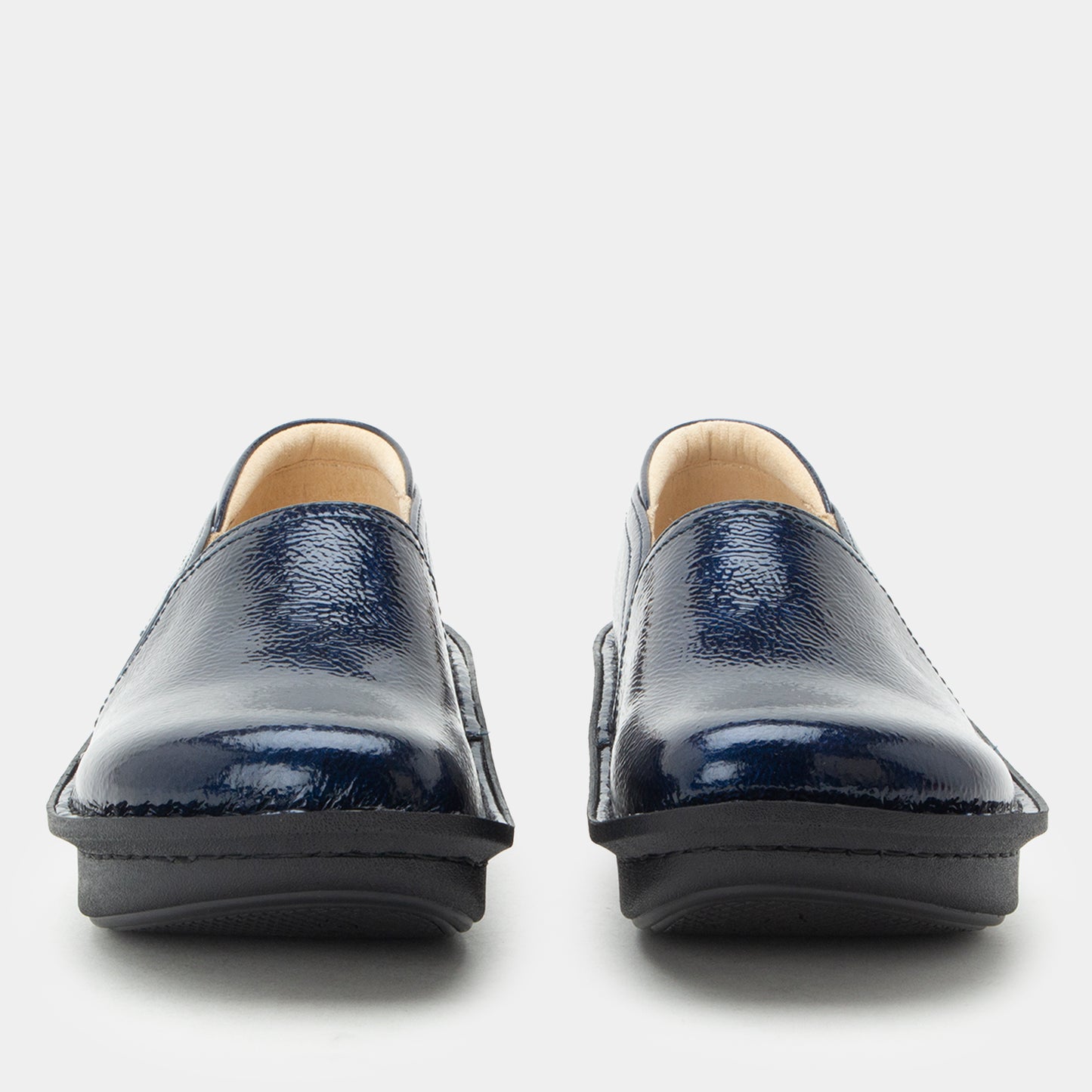 A pair of navy blue patent leather slip-on shoes with black soles, shown from the front against a light gray background.