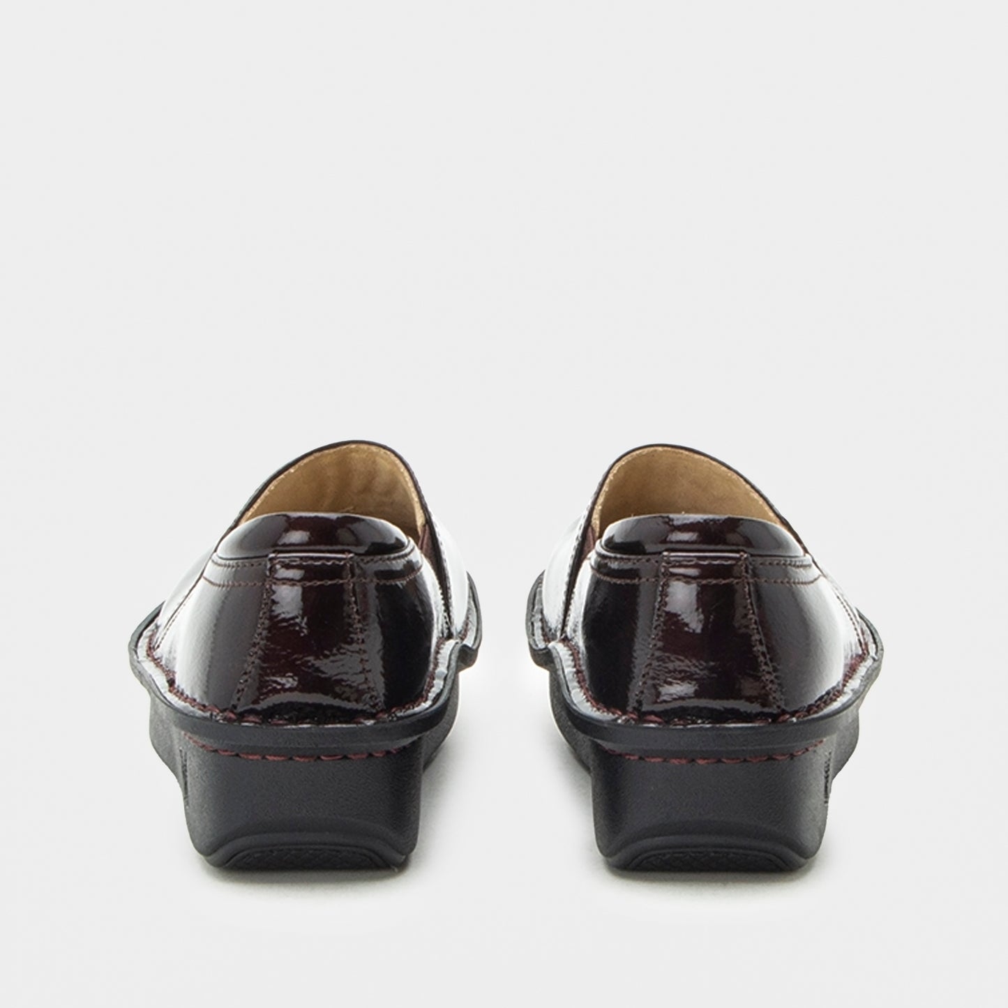 A pair of women's patent leather loafers shown from the back, featuring a glossy deep burgundy finish with black platform soles and contrast stitching.