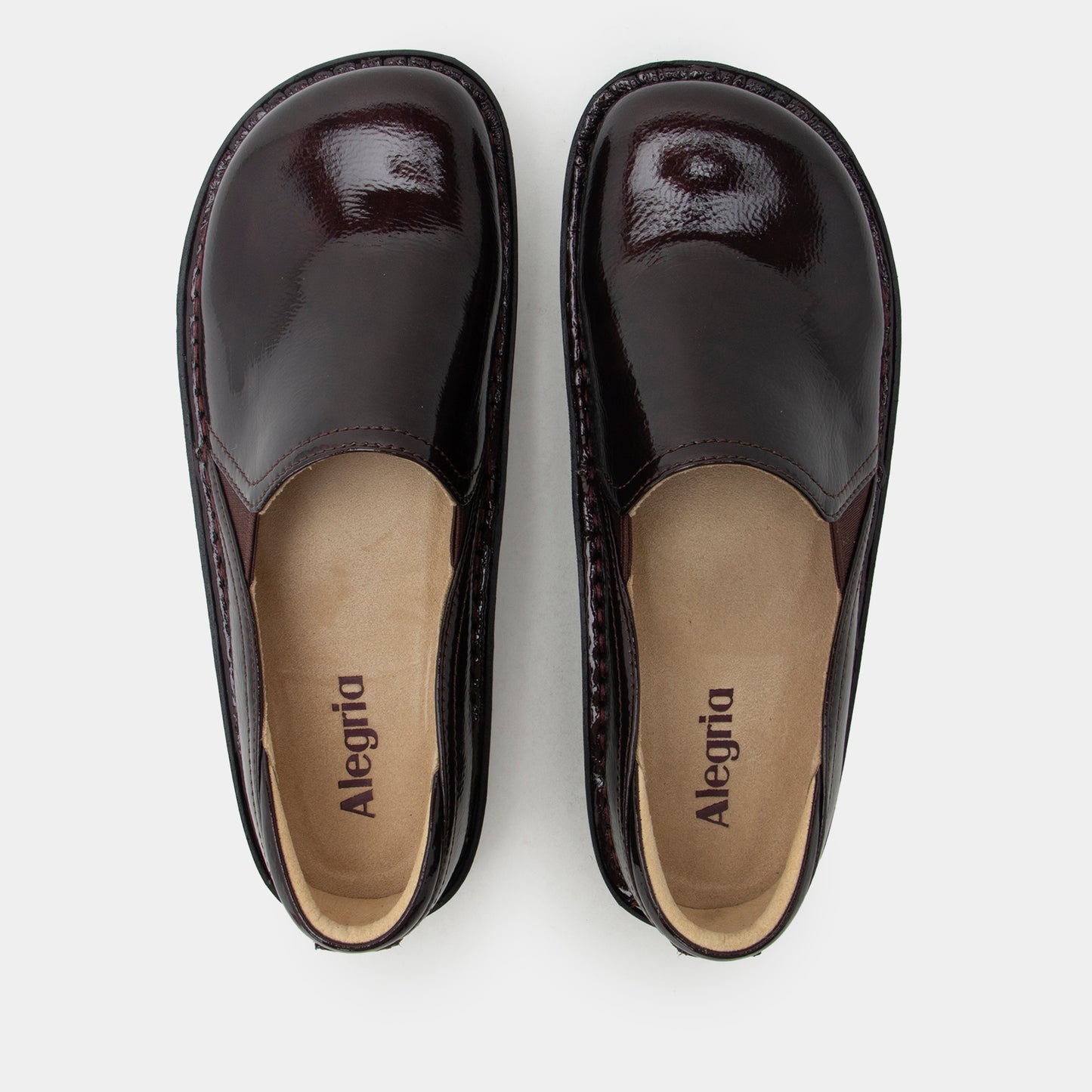 A pair of Alegria deep burgundy patent leather slip-on shoes, shown from a top-down view on a light gray background.