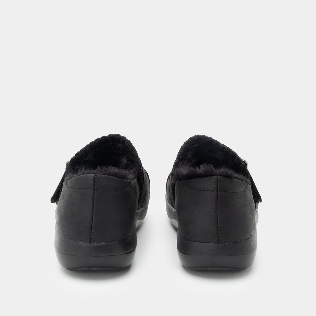 A pair of black slip-on slippers with plush black faux-fur lining, shown from the back against a light gray background.