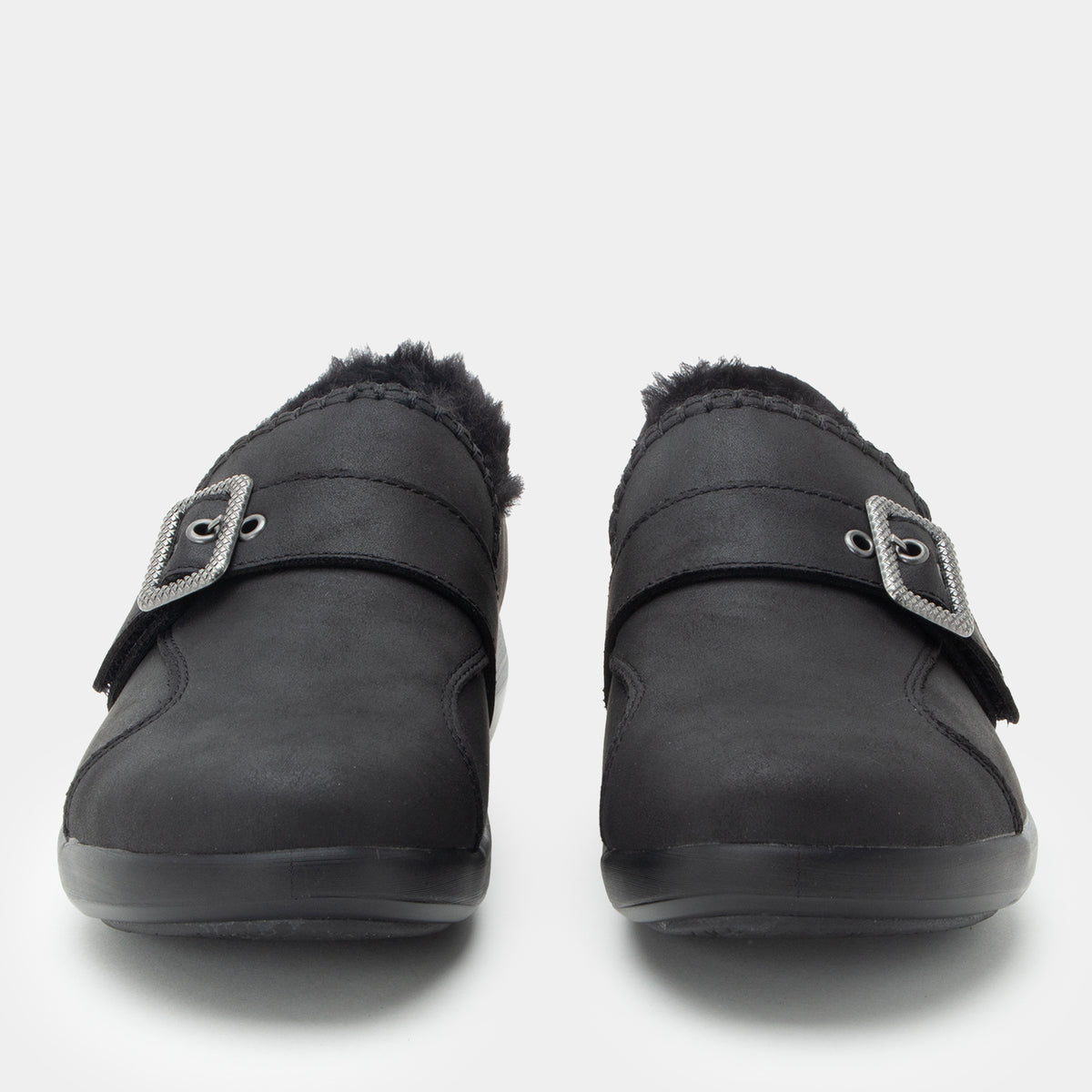 A pair of black slip-on slippers with faux fur lining and a decorative silver buckle strap, shown from a front-facing perspective on a light gray background.