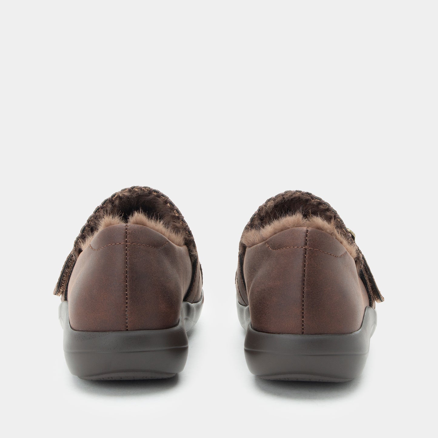 A pair of women's slip-on shoes shown from the back, featuring a dark brown leather upper, a brown and black faux-fur collar, and a dark gray sole, set against a plain light gray background.