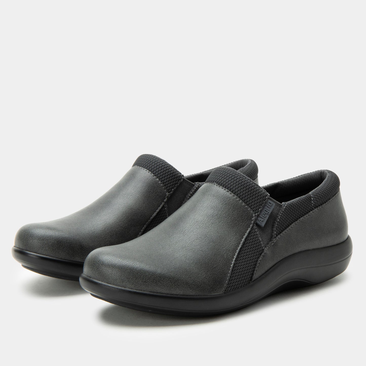 Pair of gray slip-on shoes with black straps on a light gray background
