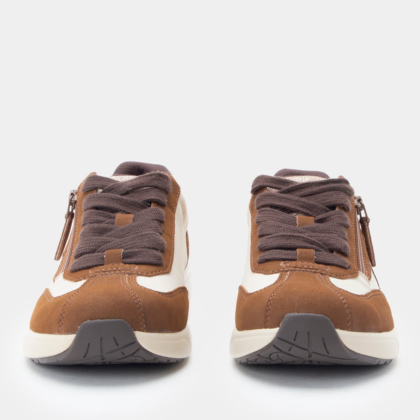 Pair of brown and white sneakers with zippers on a light gray background