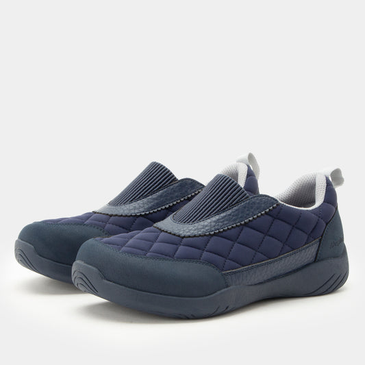 A pair of navy blue slip-on quilted shoes with gray ribbed knit collar panels and gray interior lining, shown on a light gray background.