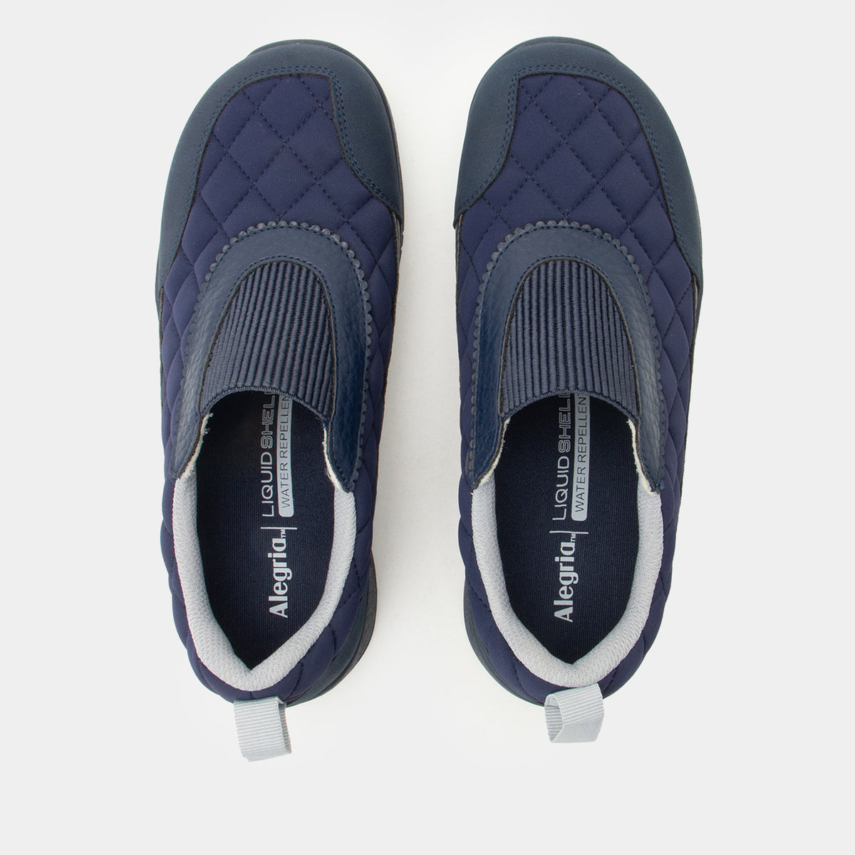 A pair of navy blue slip-on quilted shoes with gray ribbed trim and white interior lining, shown from a top-down view on a light gray background.
