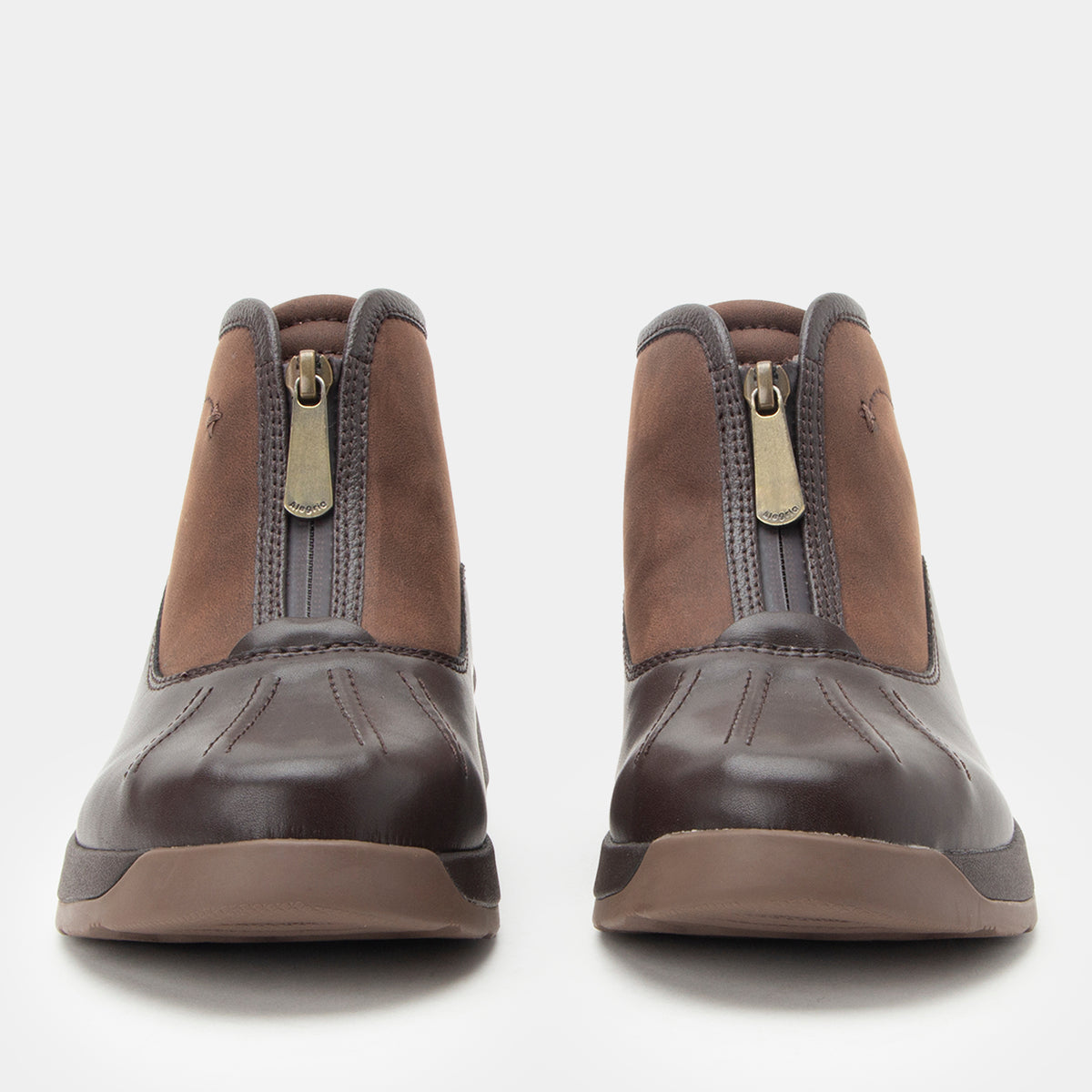 A pair of brown ankle boots with a dark brown rubber toe cap and a silver-tone zipper on the back, shown from the front against a light gray background.