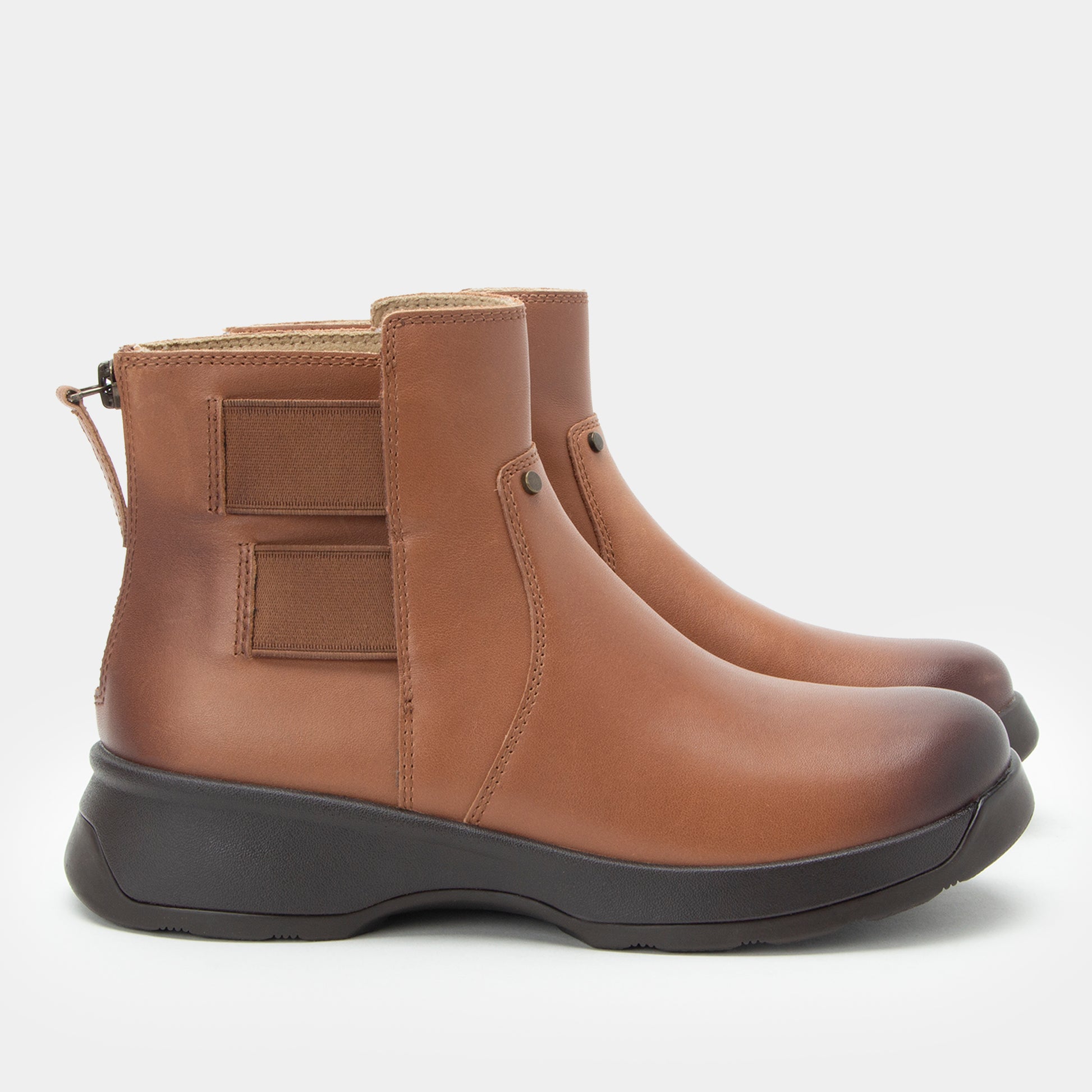 Pair of brown leather boots with black soles on a light gray background