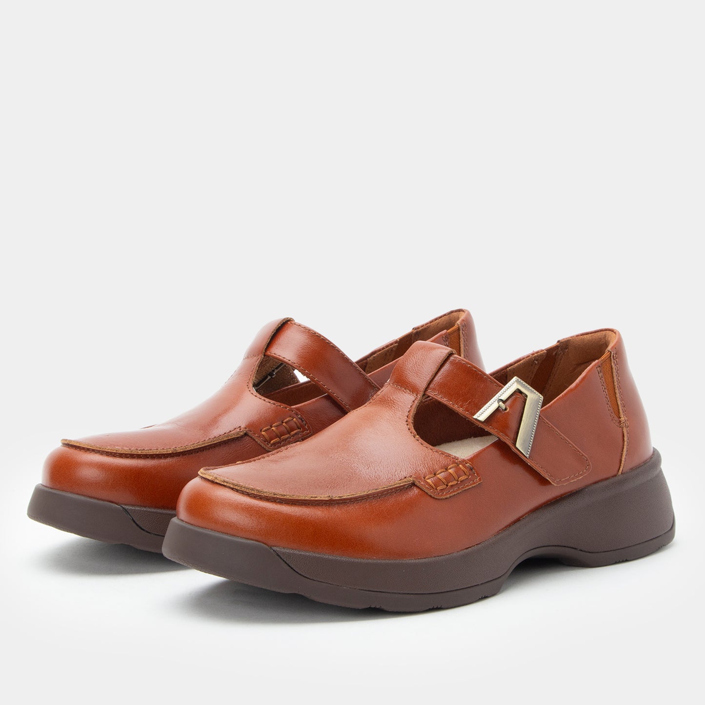 Pair of brown shoes with a strap on a light gray background