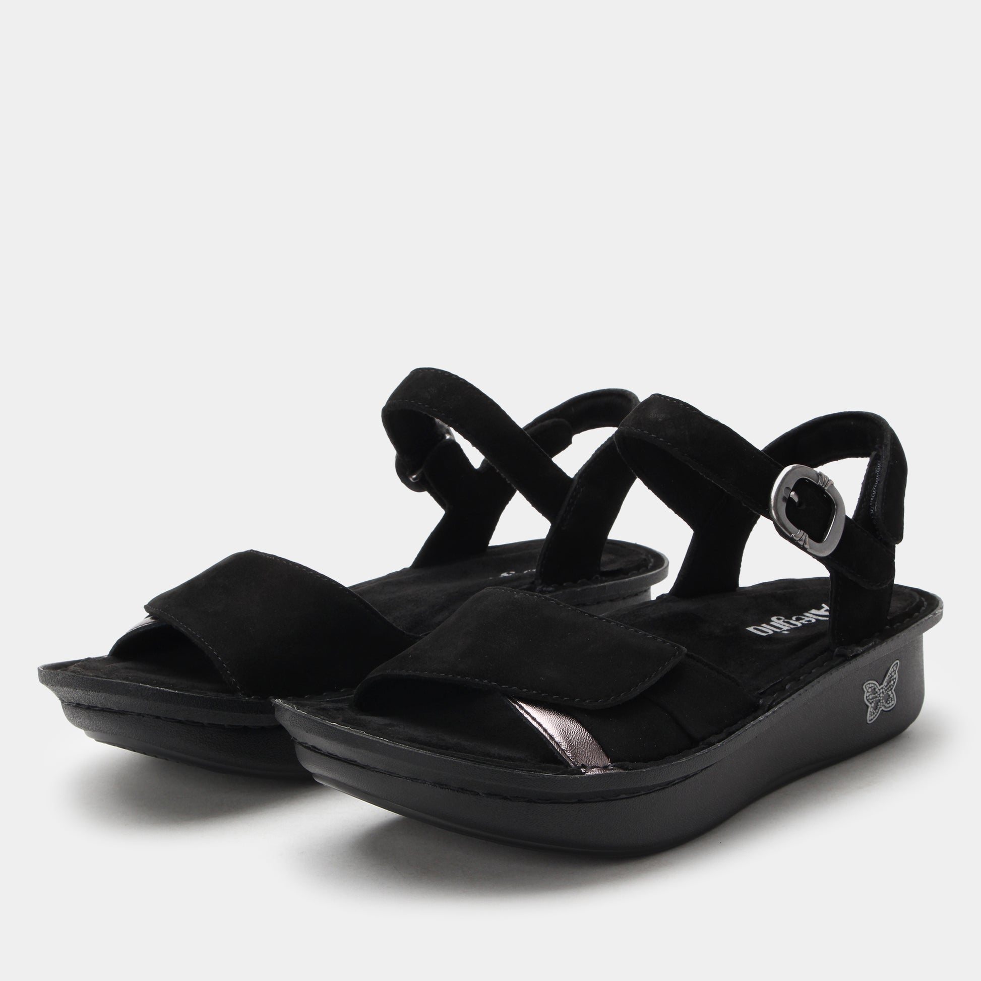 Black sandals with criss-cross straps on a light gray background