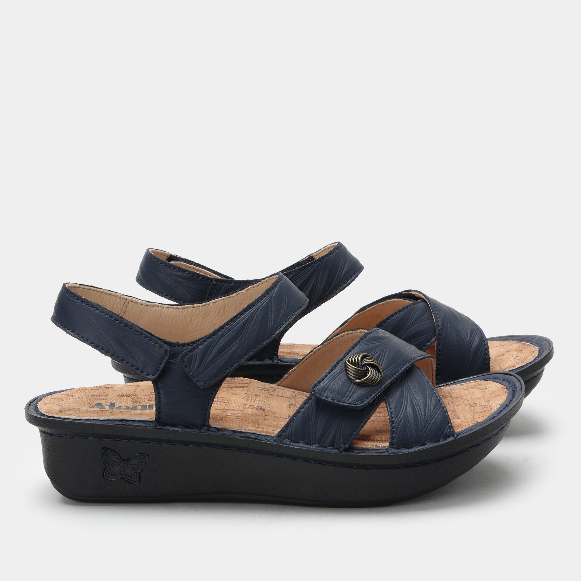 Navy blue sandals with a black sole on a light gray background