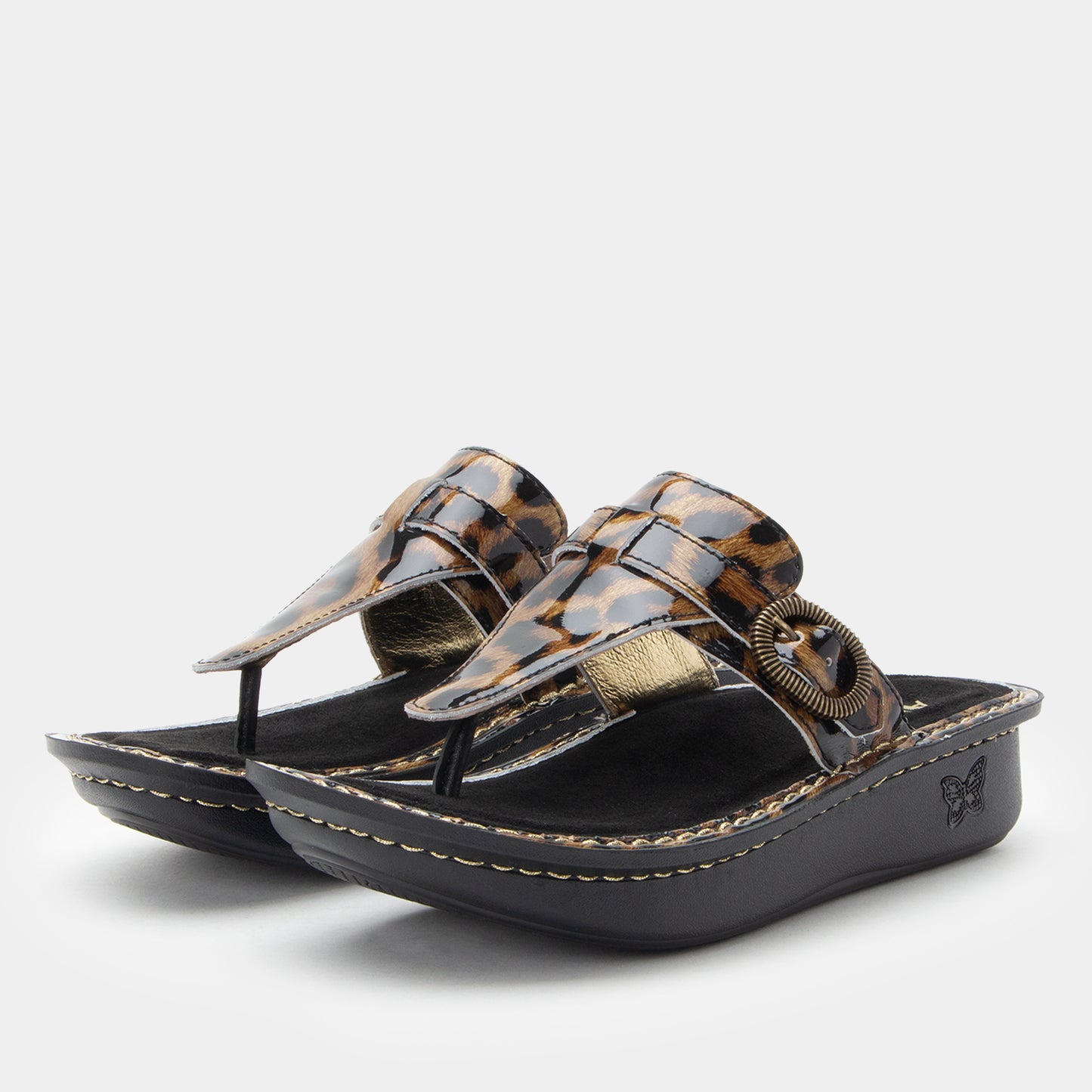 Pair of leopard print sandals with gold accents on a light gray background