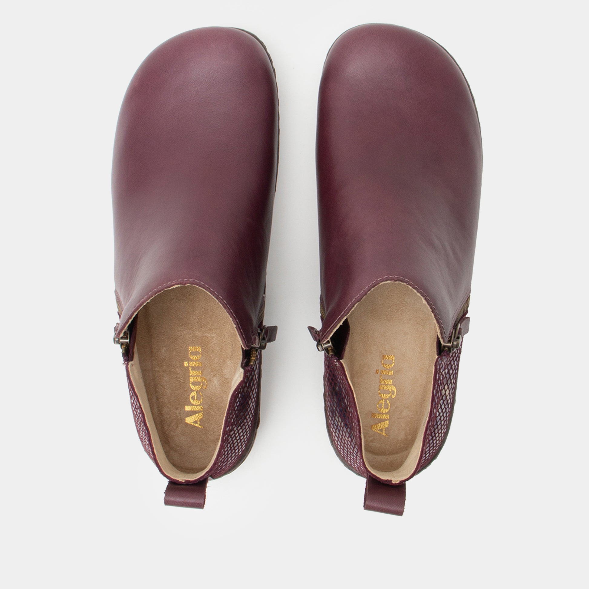 Pair of purple leather clogs on a white background