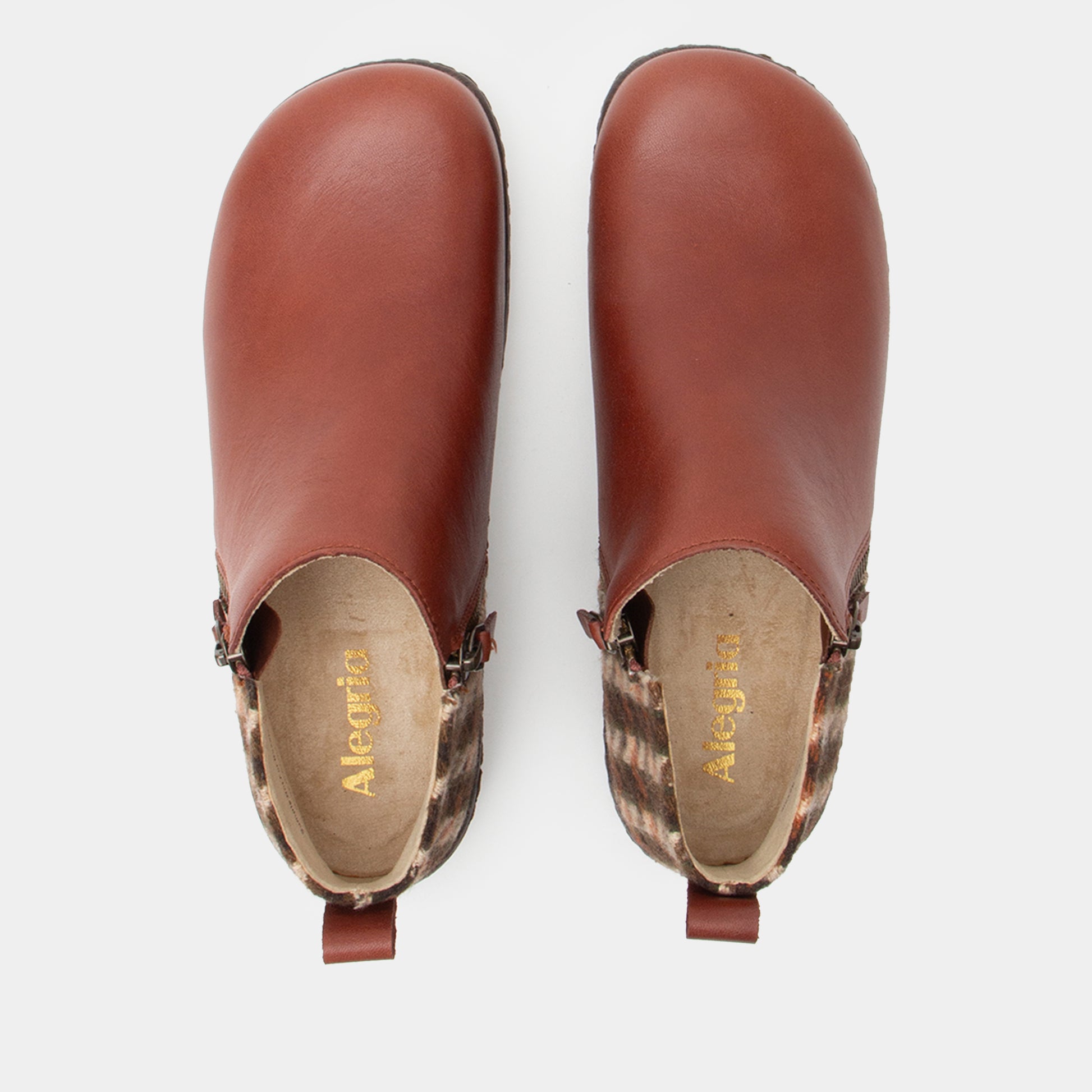 Pair of brown leather clogs with patterned soles on a white background
