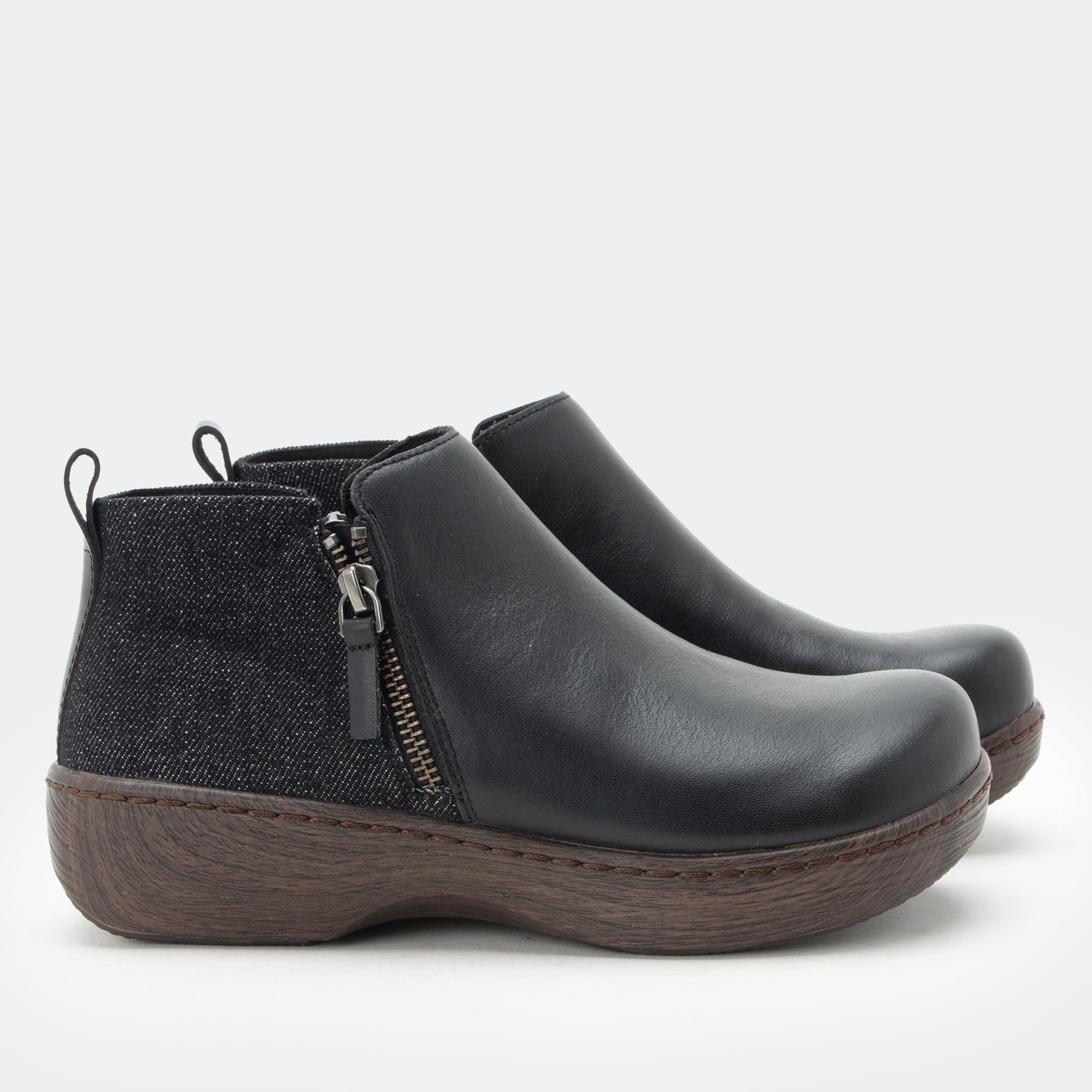 Pair of black ankle boots with a zipper on a light gray background