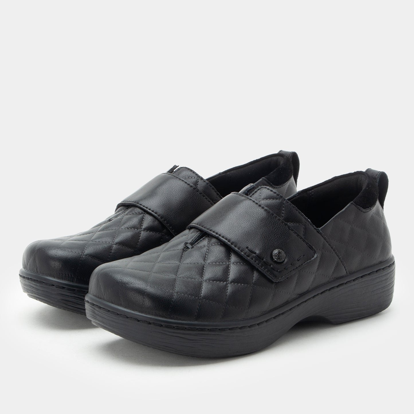 Pair of black quilted shoes on a white background