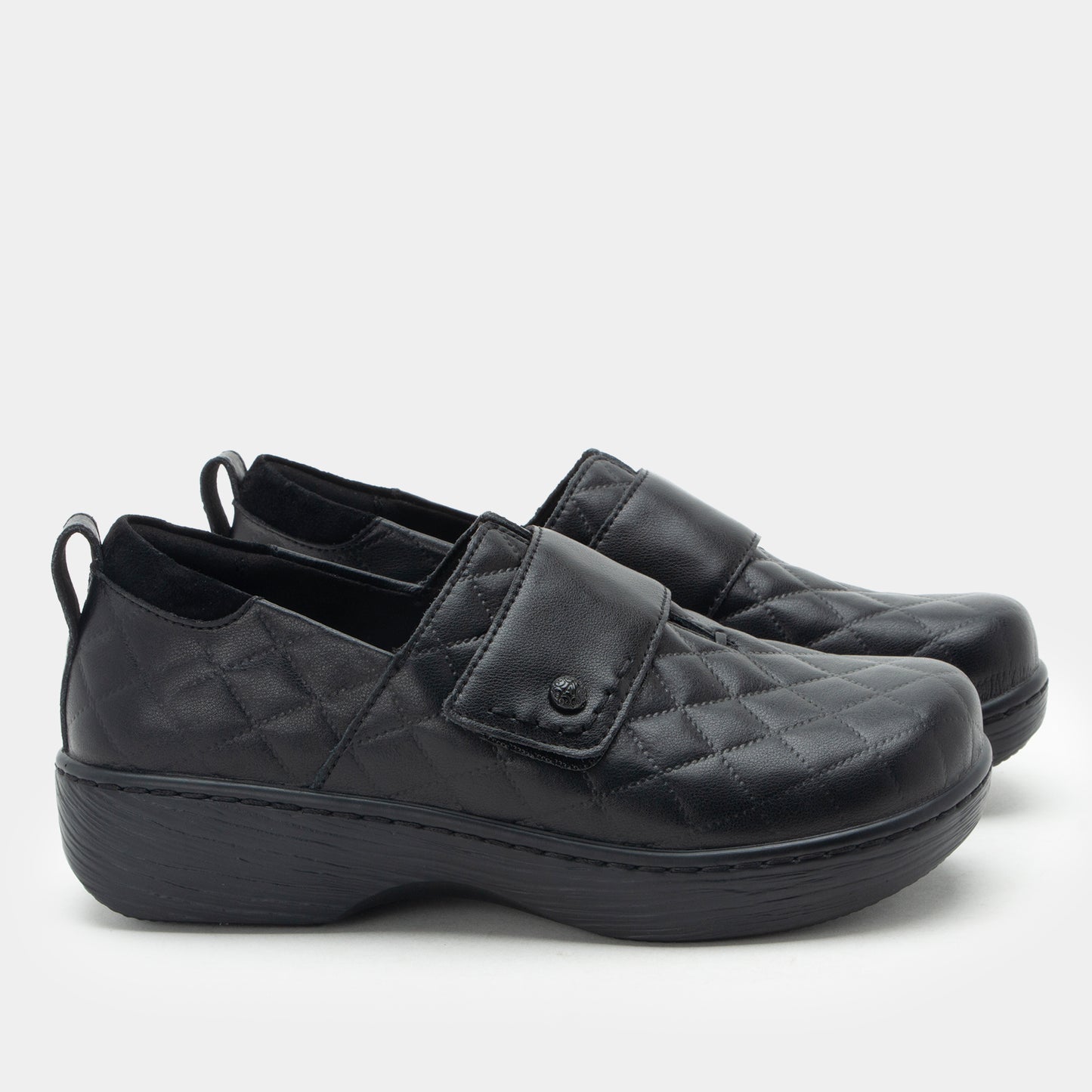 Pair of black slip-on shoes with velcro straps on a white background