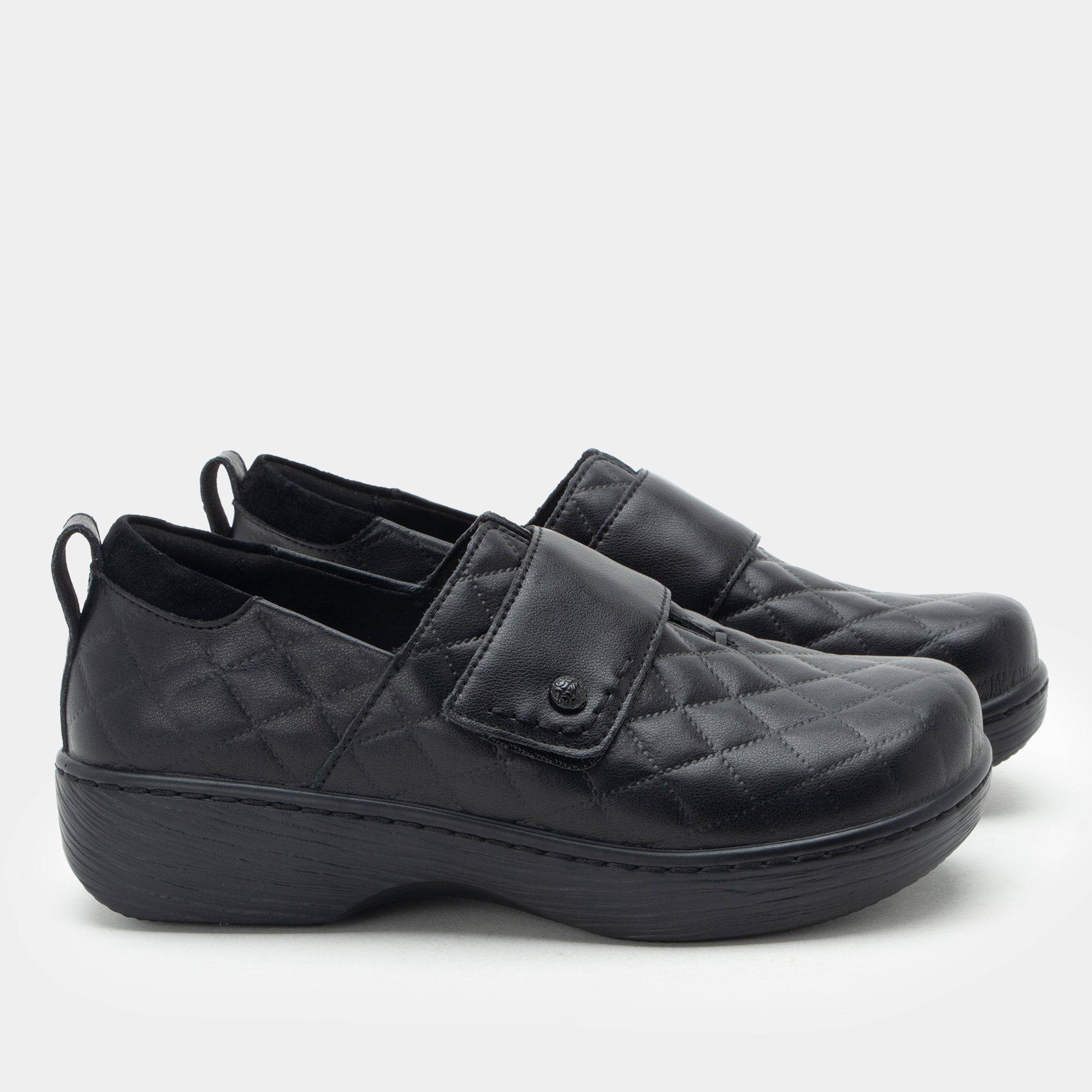 Pair of black slip-on shoes with velcro straps on a white background