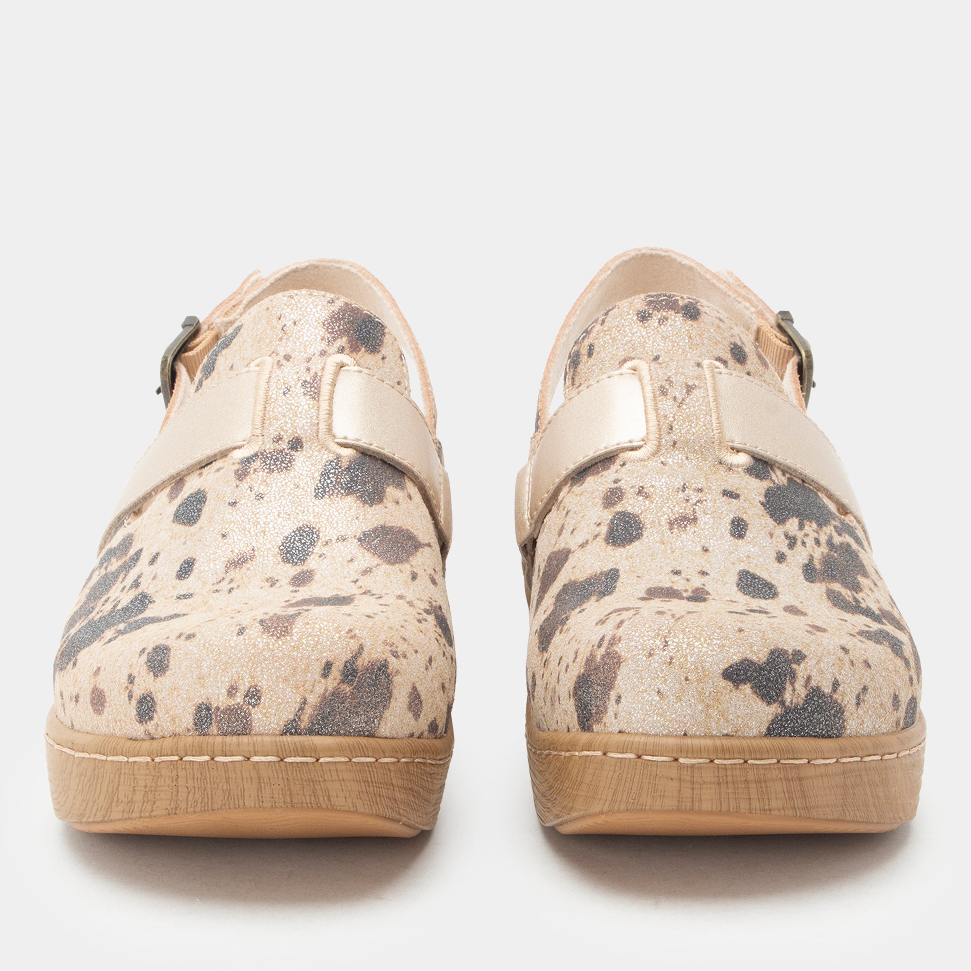 A pair of slip-on shoes with a beige and gray speckled pattern, featuring a light beige strap across the top and a light tan sole, shown against a plain light gray background.